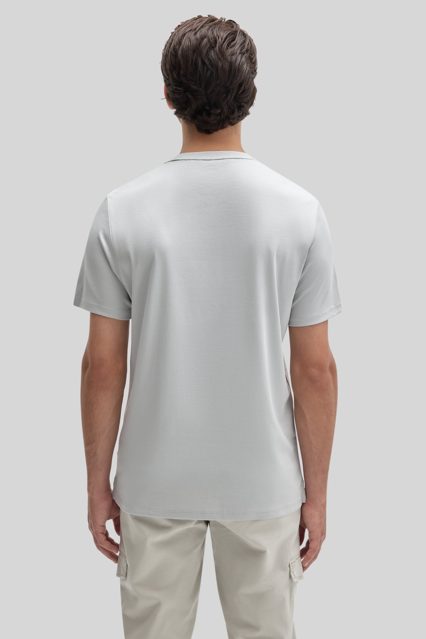 Man wearing white short-sleeve t-shirt and beige cargo pants, shown from behind.
