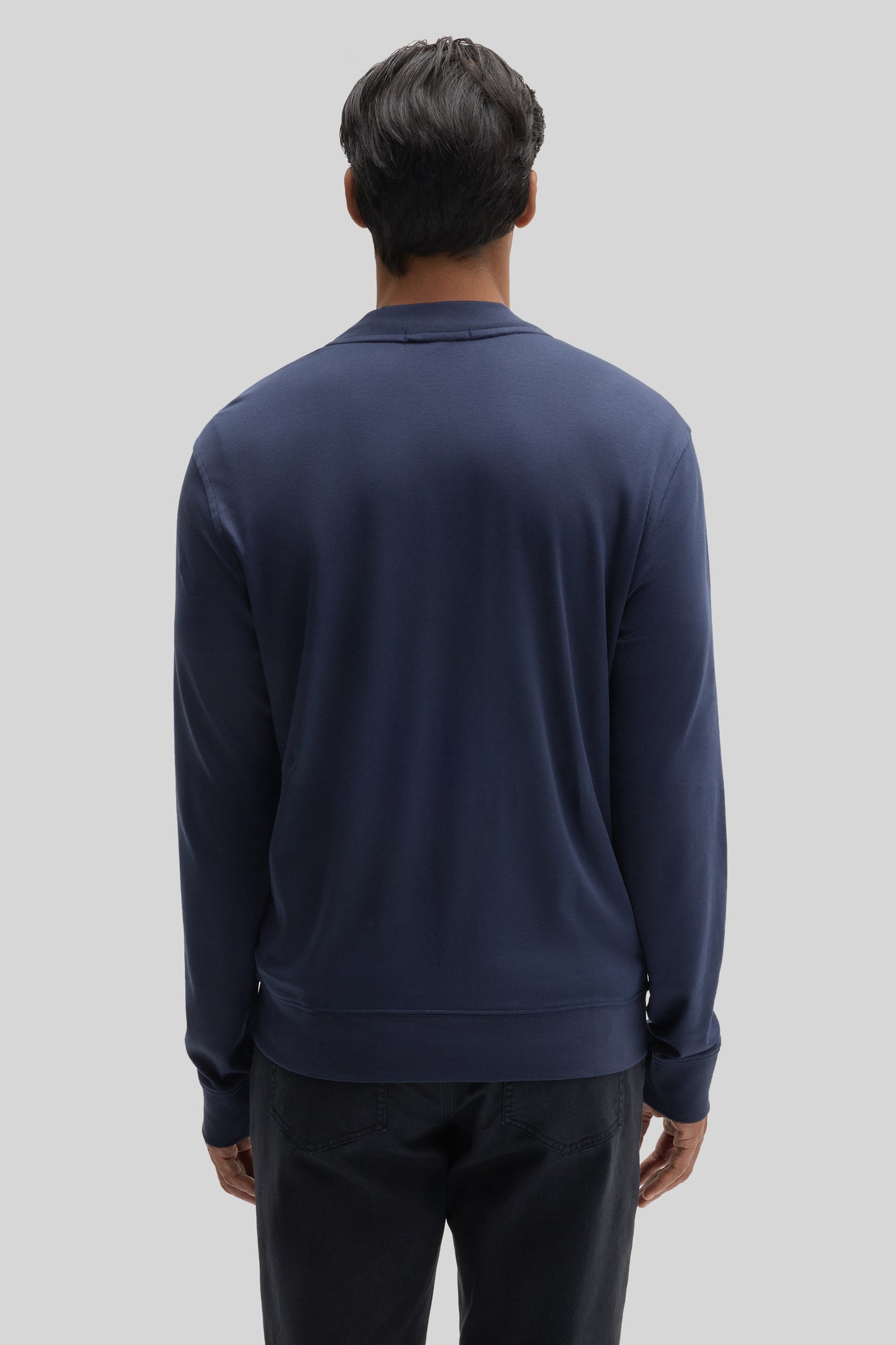 Man wearing navy blue baseball jacket with collar, shown from back view.