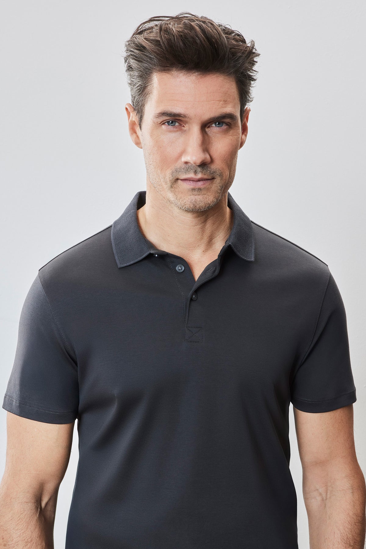 Man wearing dark navy polo shirt with short sleeves and buttoned collar.