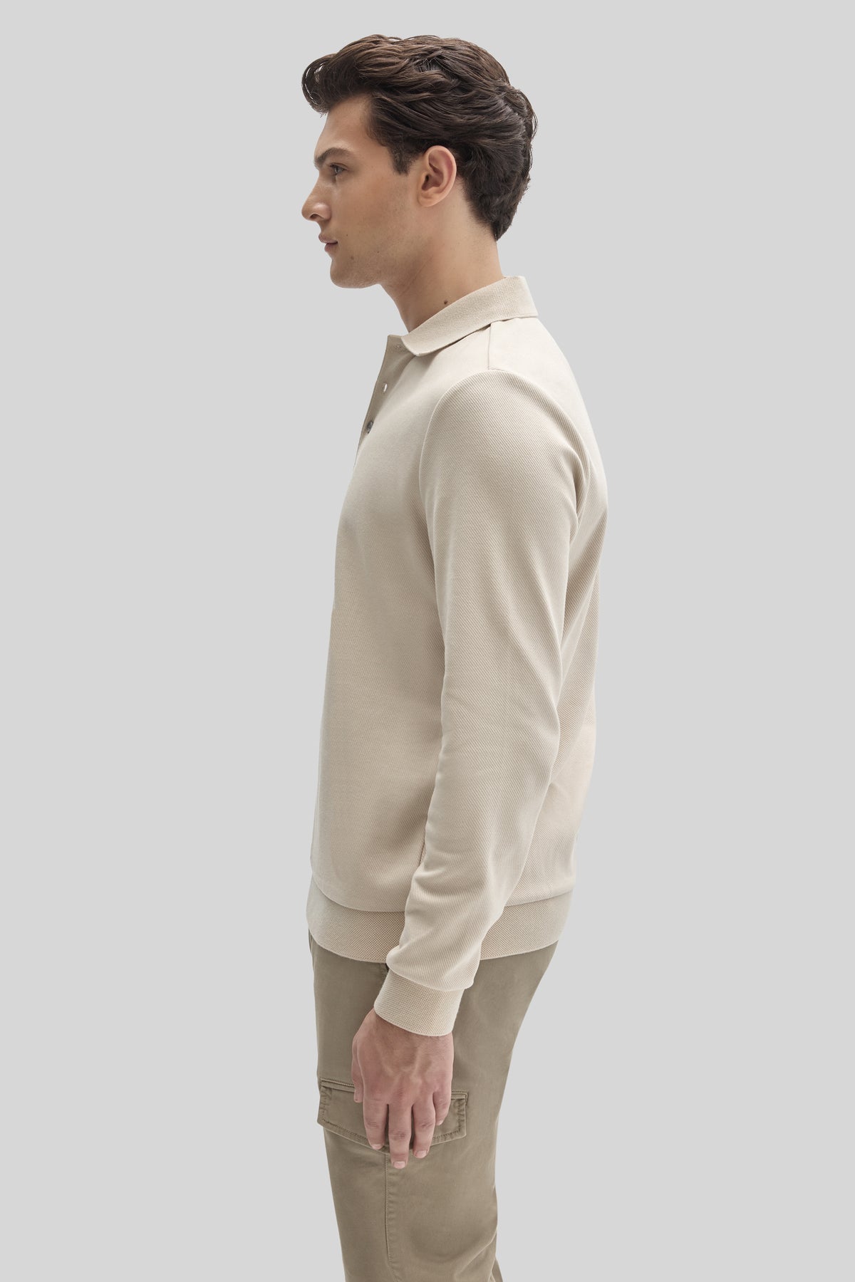 Man wearing cream long sleeve polo shirt with collar, shown in profile view.
