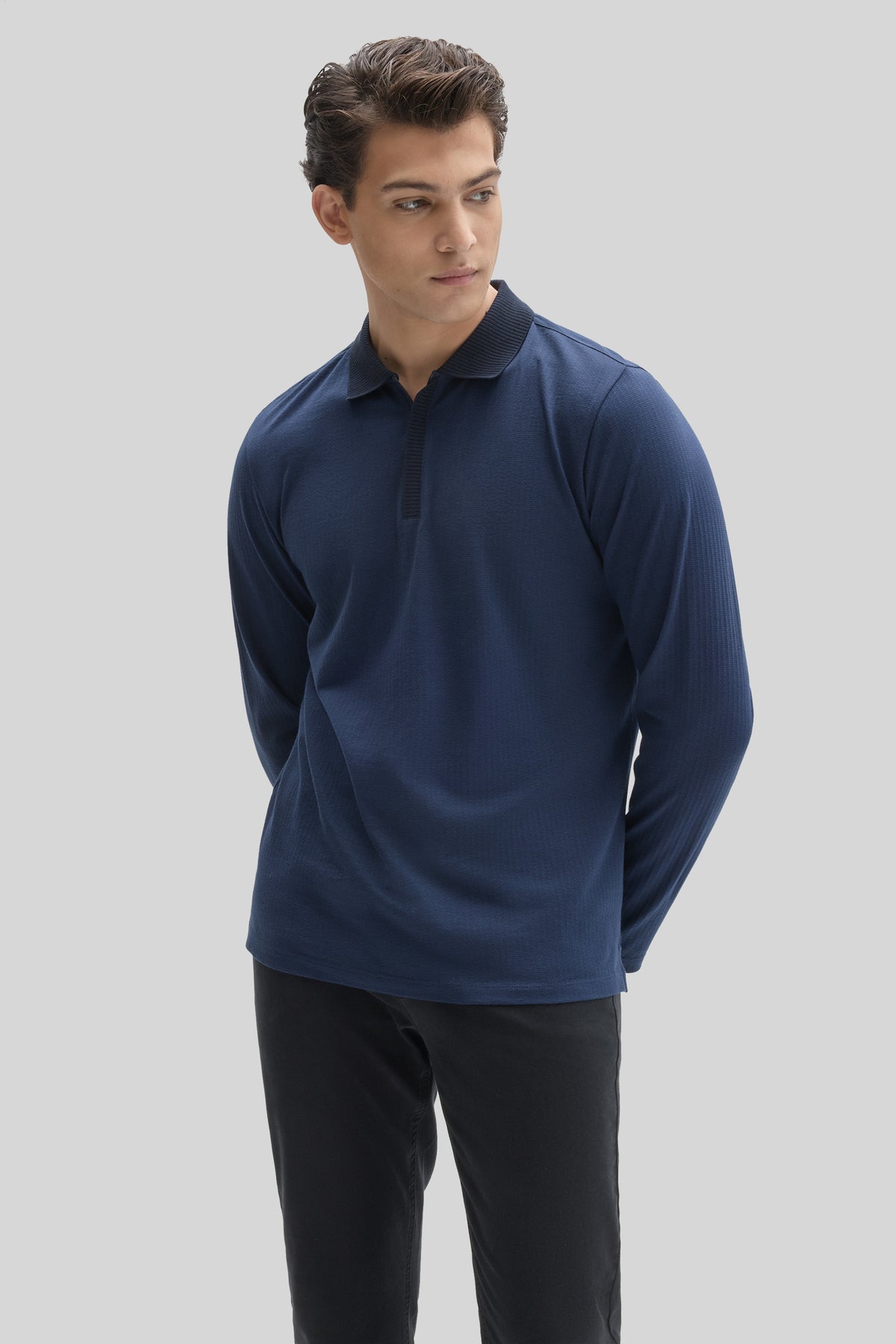 Man wearing navy long-sleeve polo with zip placket and ribbed collar, paired with black pants.