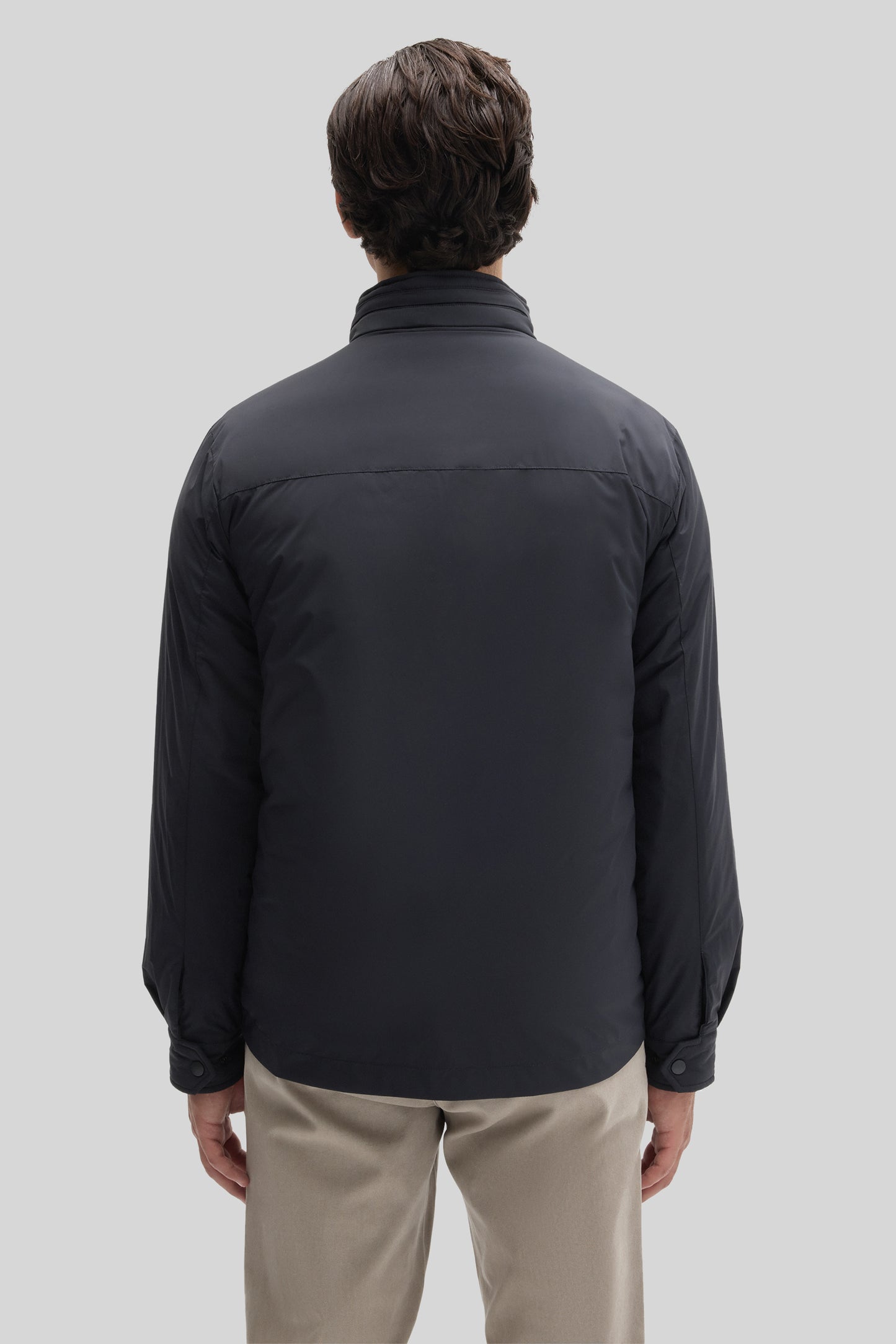Black snap jacket with collared neckline, shown from back on model wearing beige pants.