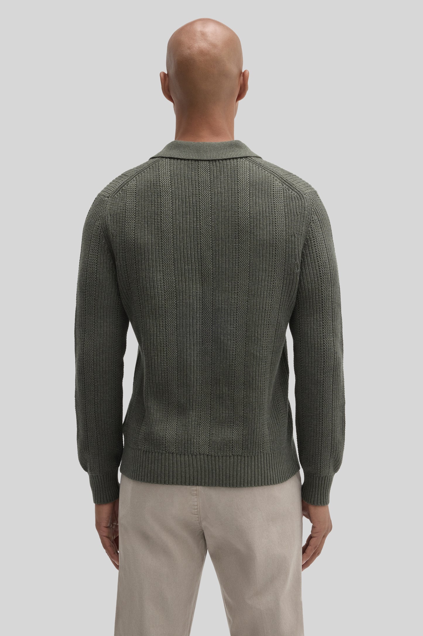 Sage green ribbed sweater polo with collar, viewed from back on male model wearing beige pants.