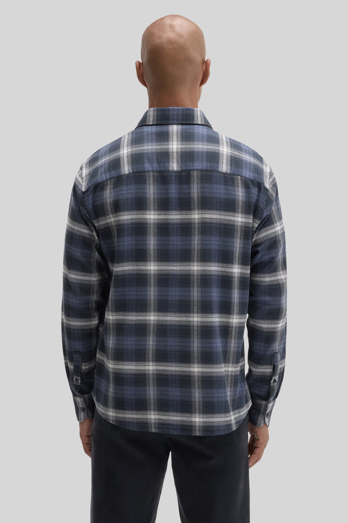 Navy and white plaid corduroy shirt with long sleeves and button cuffs, shown from back view on model.