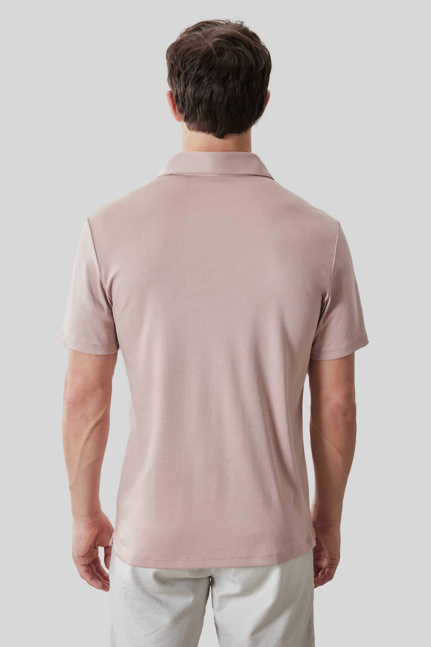 Man wearing a beige short-sleeved polo shirt with collar, shown from behind.