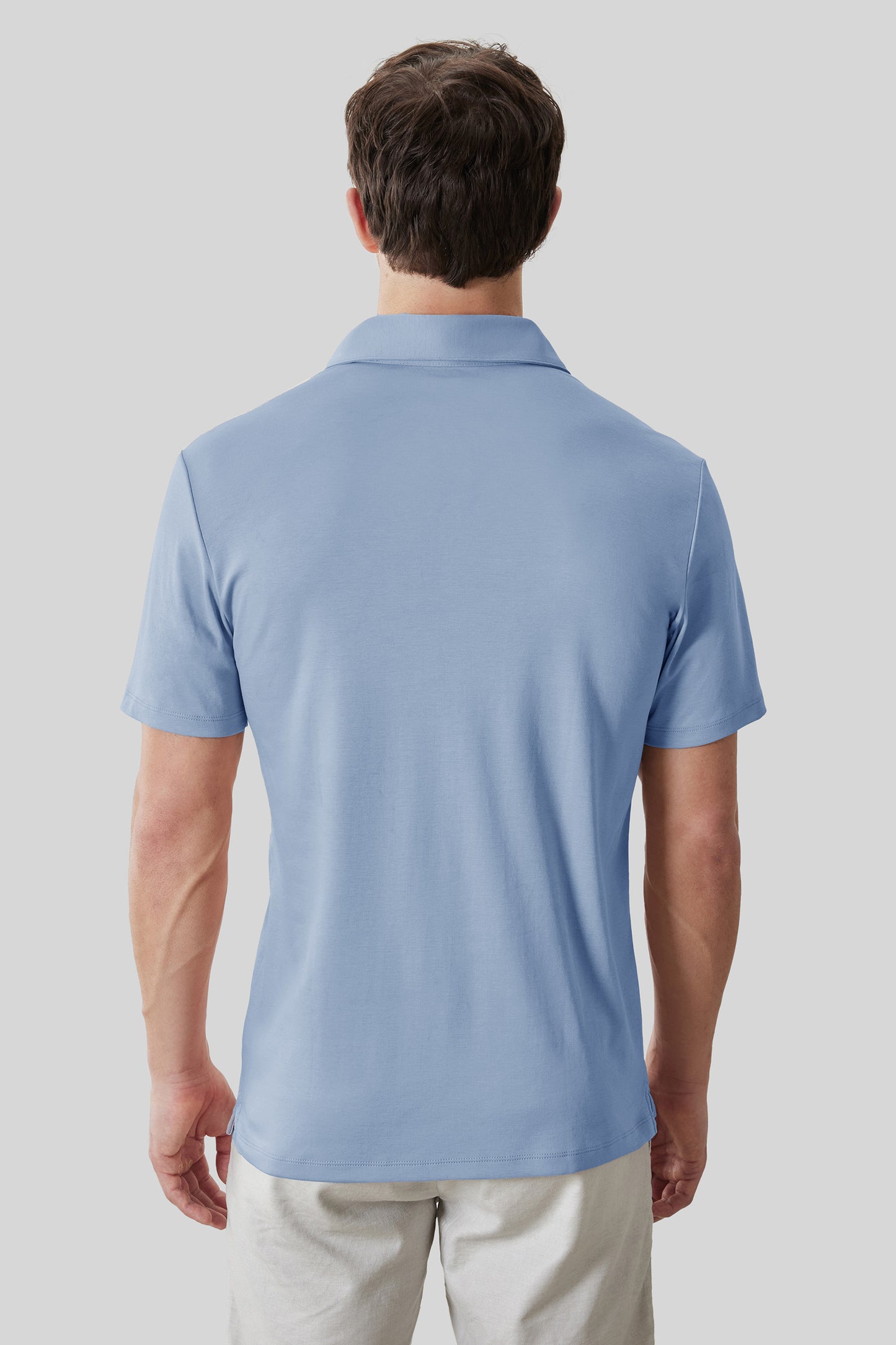 Man wearing light blue short-sleeve polo shirt with collar, shown from back view.
