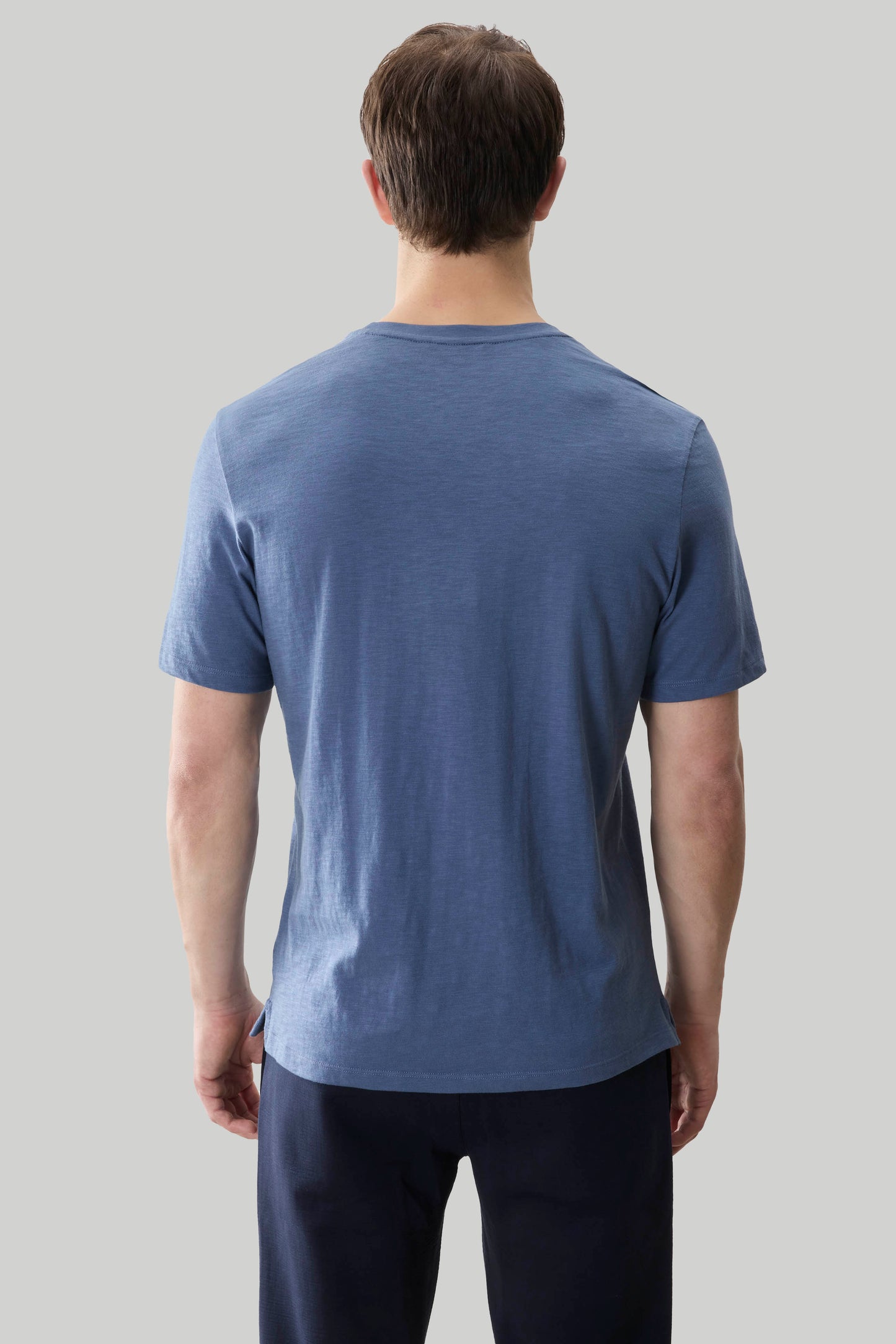 Man wearing blue short-sleeve t-shirt, back view.