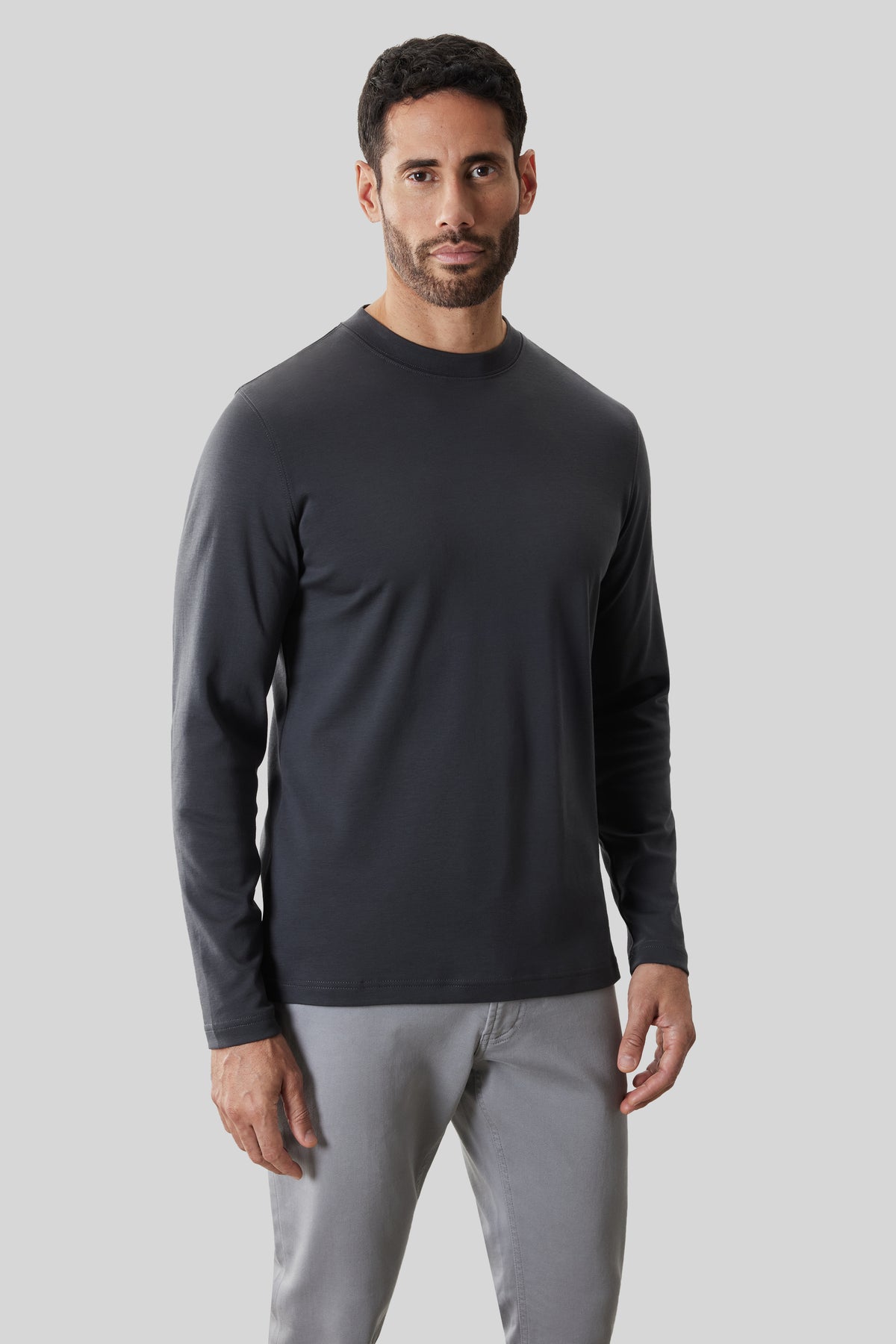 Man wearing black long-sleeve crew neck shirt with gray pants.