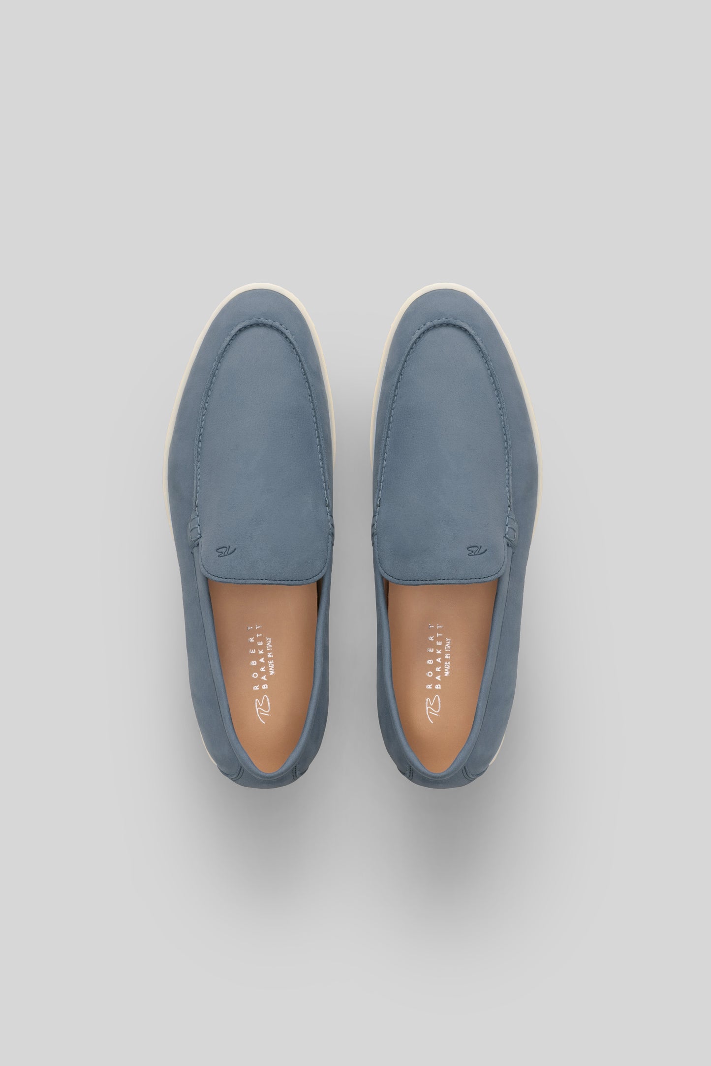 Pair of blue suede loafers with cream soles and tan leather insoles, shown from above.