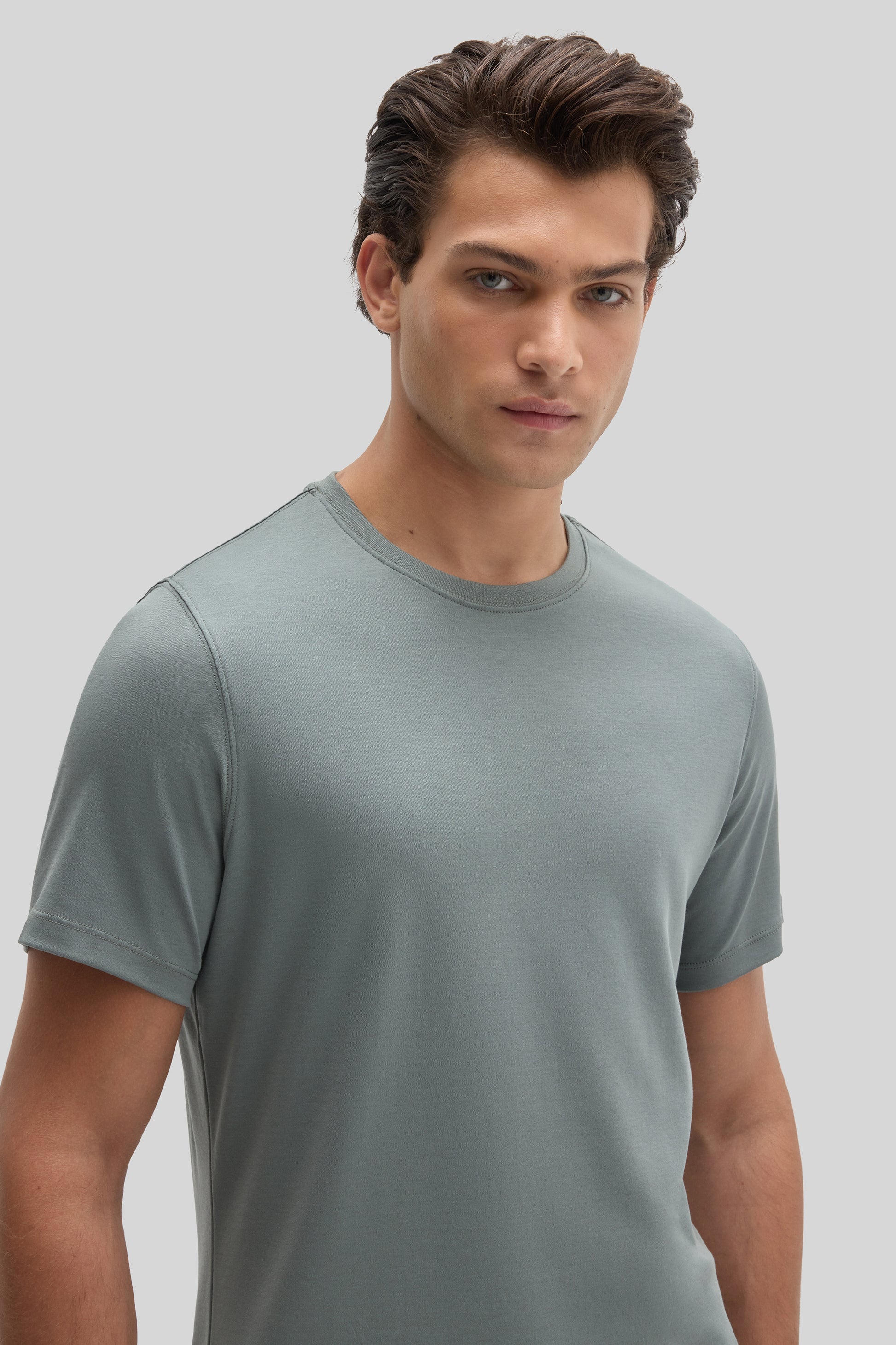Man wearing a sage green short-sleeve crew neck t-shirt against a neutral background.