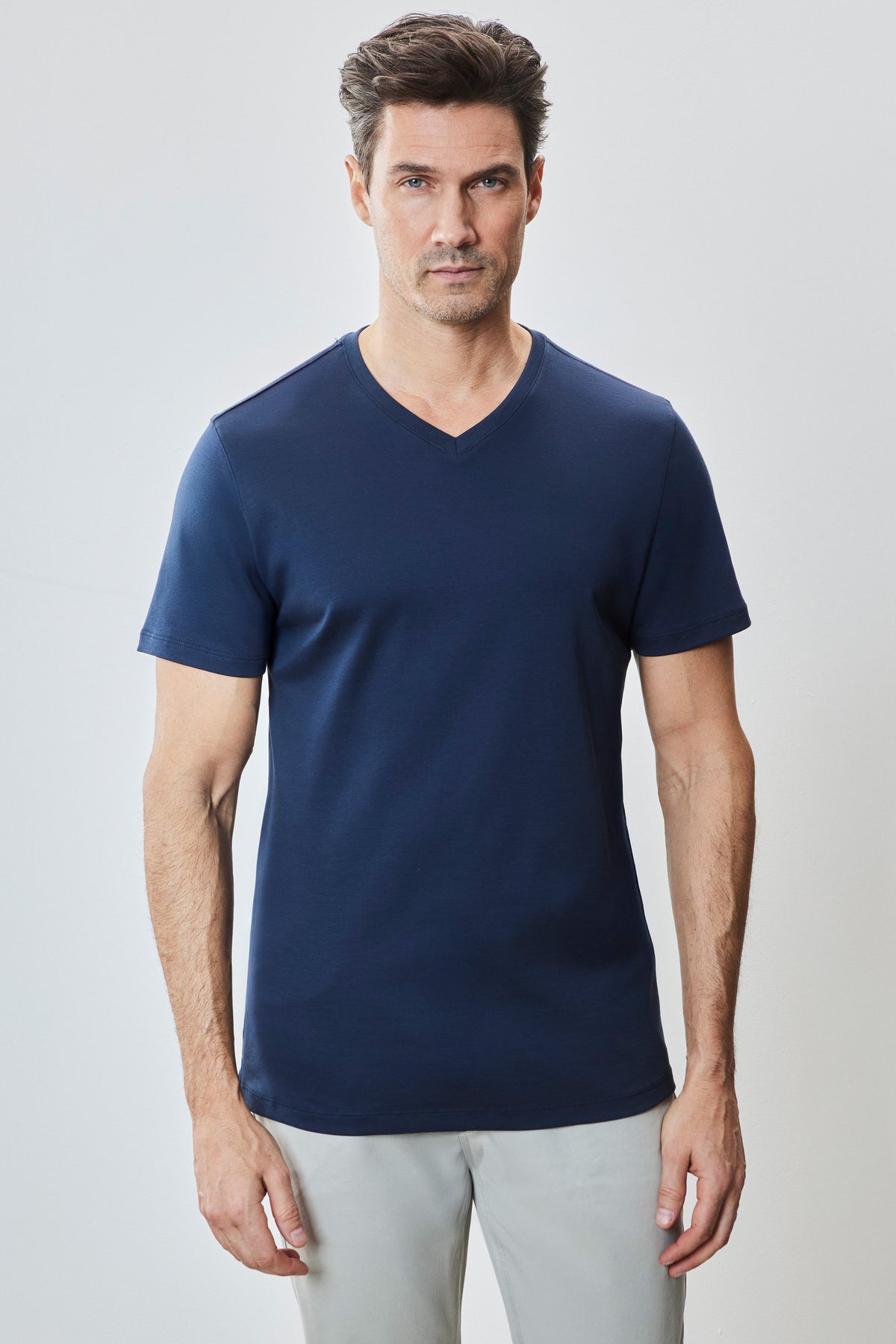 Man wearing navy blue V-neck short-sleeve t-shirt with light gray pants.