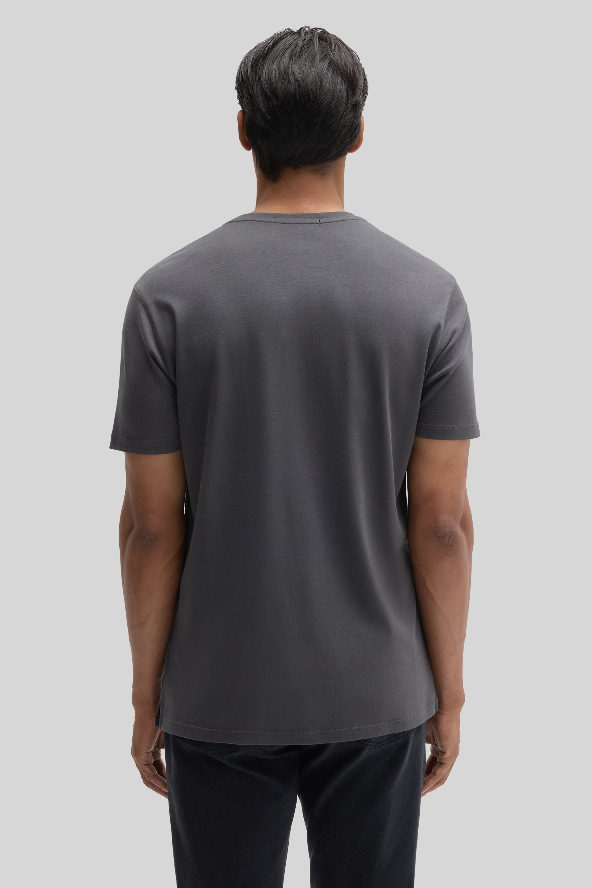 Man wearing charcoal gray V-neck short-sleeve tee with black pants, shown from back view.