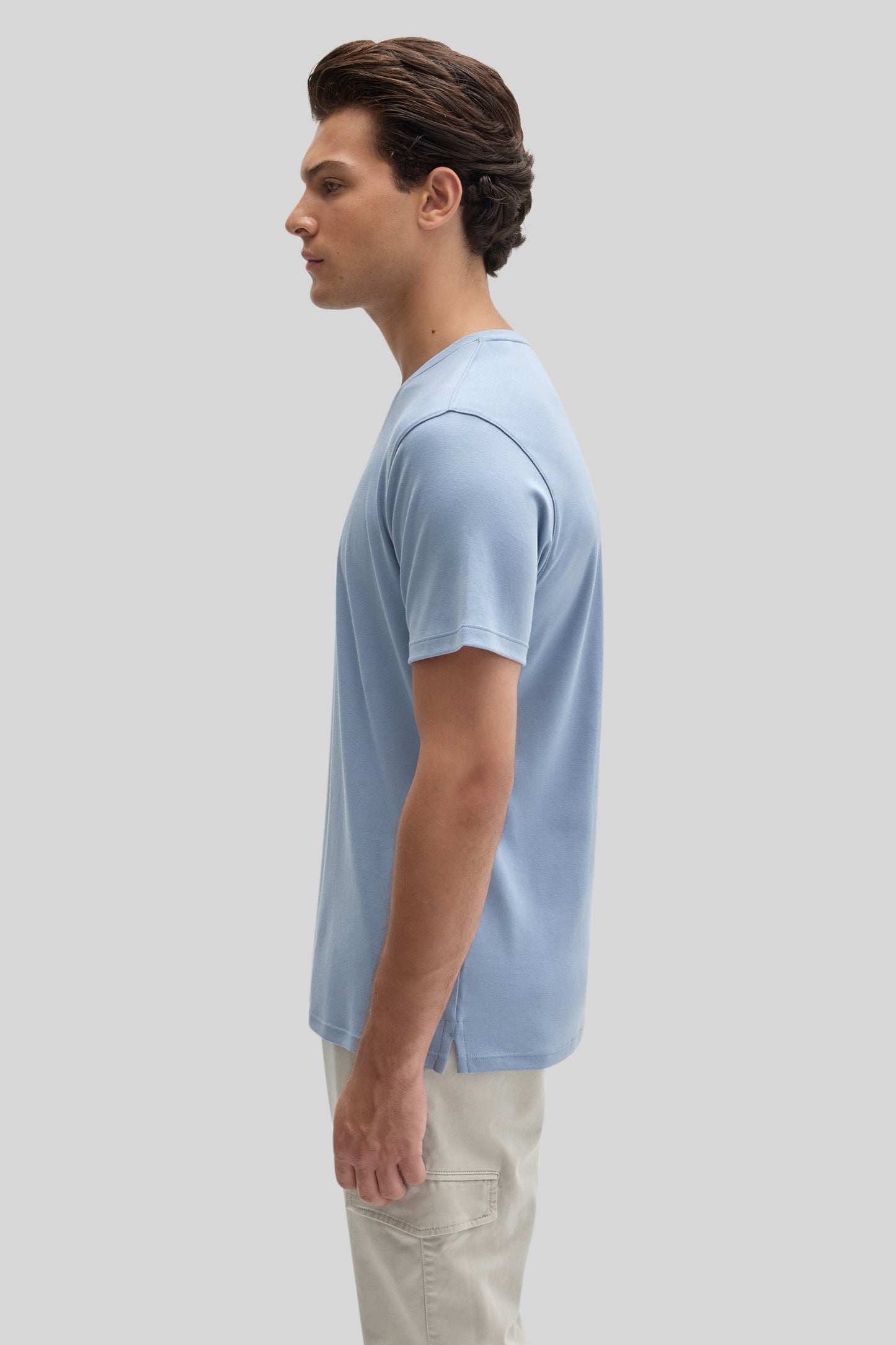 Man wearing light blue V-neck t-shirt with cream cargo pants, shown in side profile.