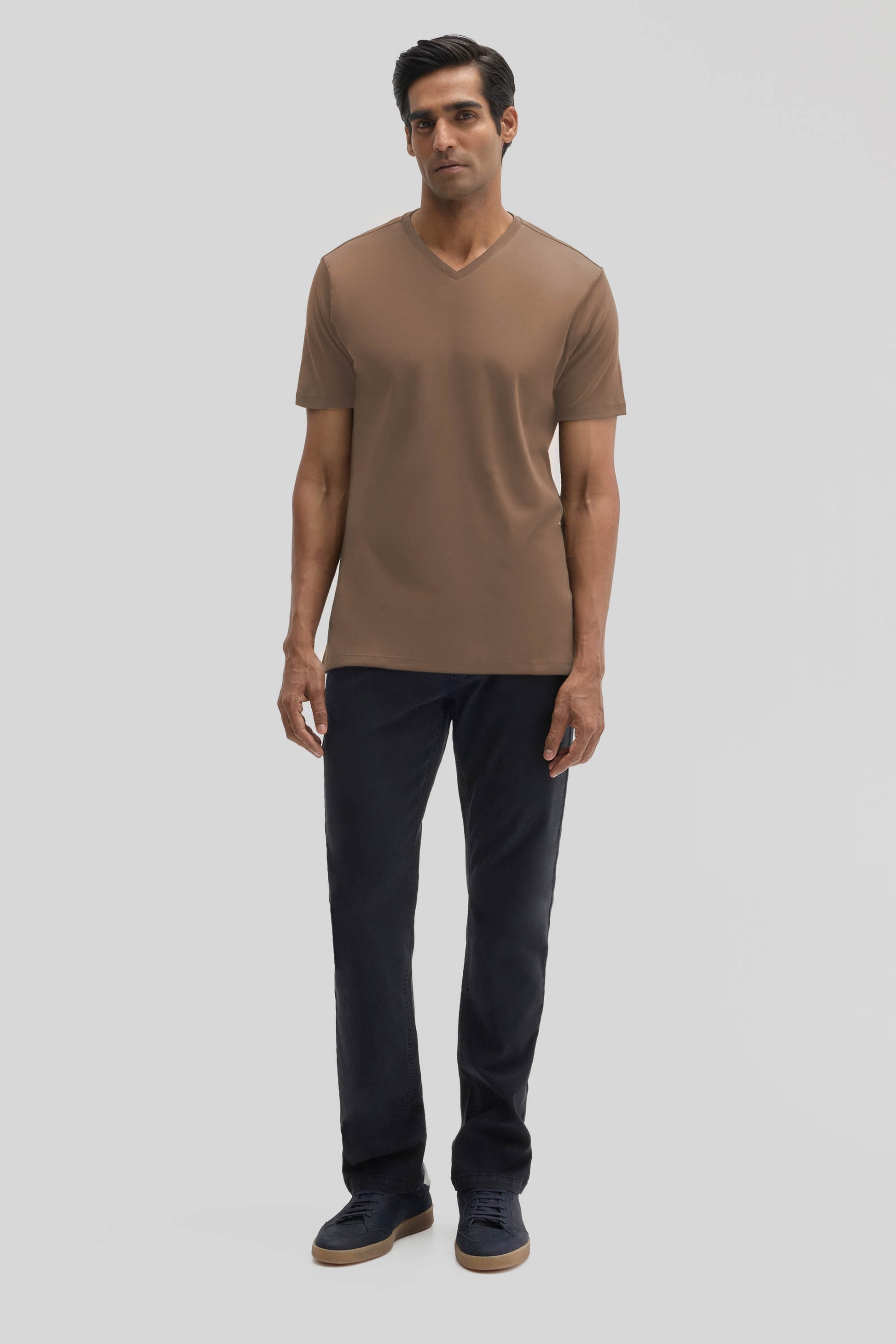 Man wearing a taupe V-neck t-shirt with short sleeves and dark navy pants.