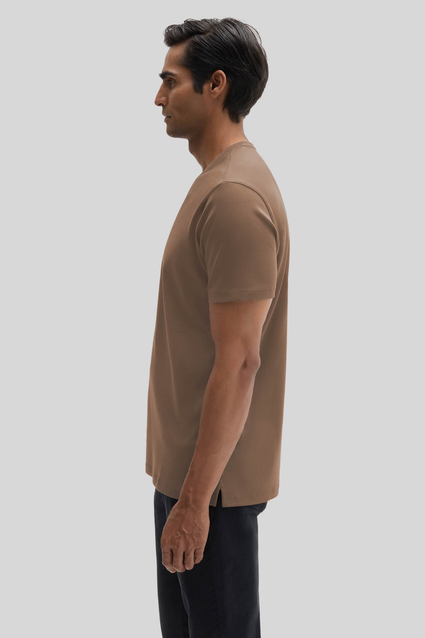 Man wearing a tan V-neck short-sleeve t-shirt with black pants.