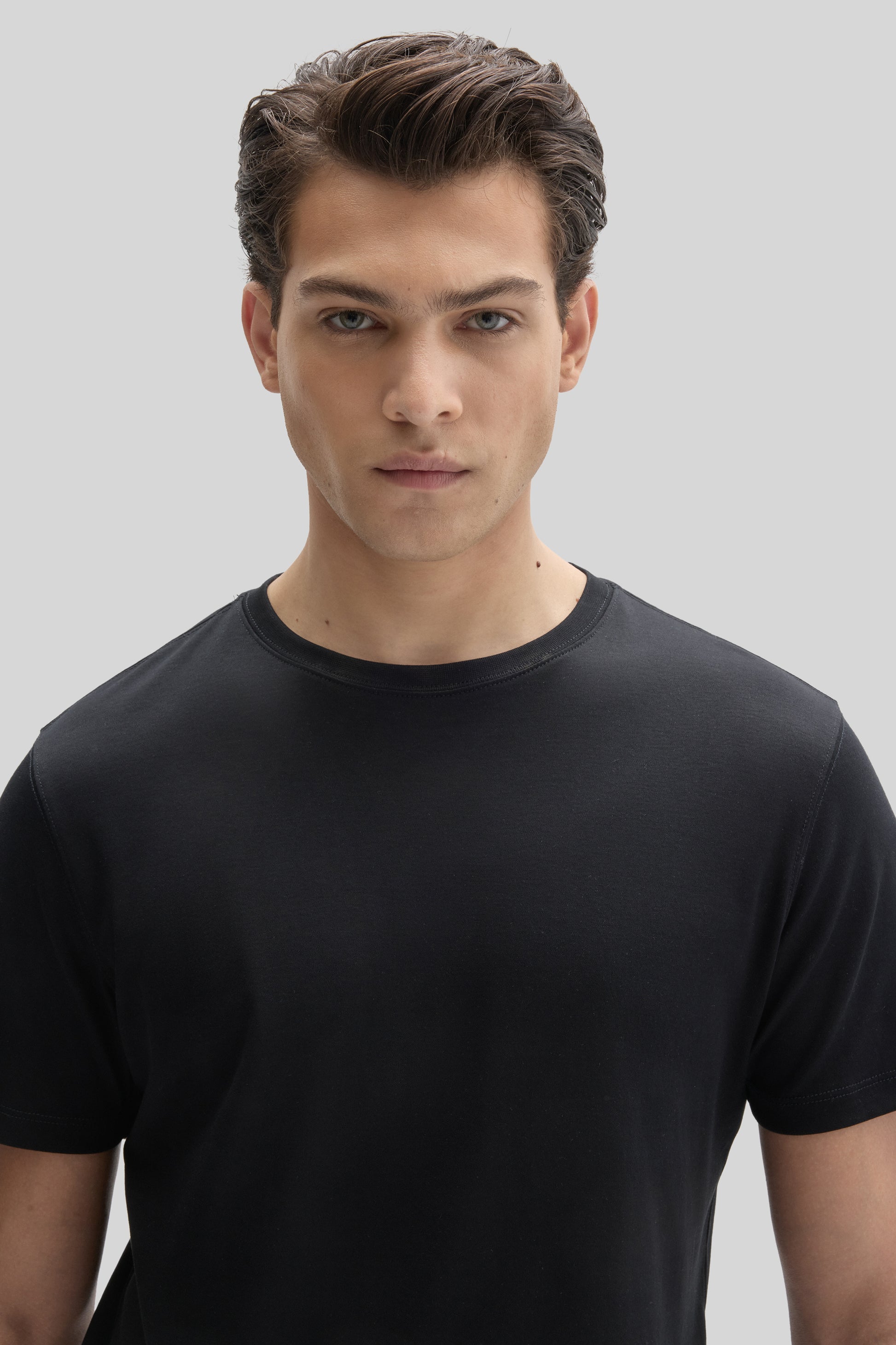 Man wearing a black crew-neck short-sleeve t-shirt against a neutral background.
