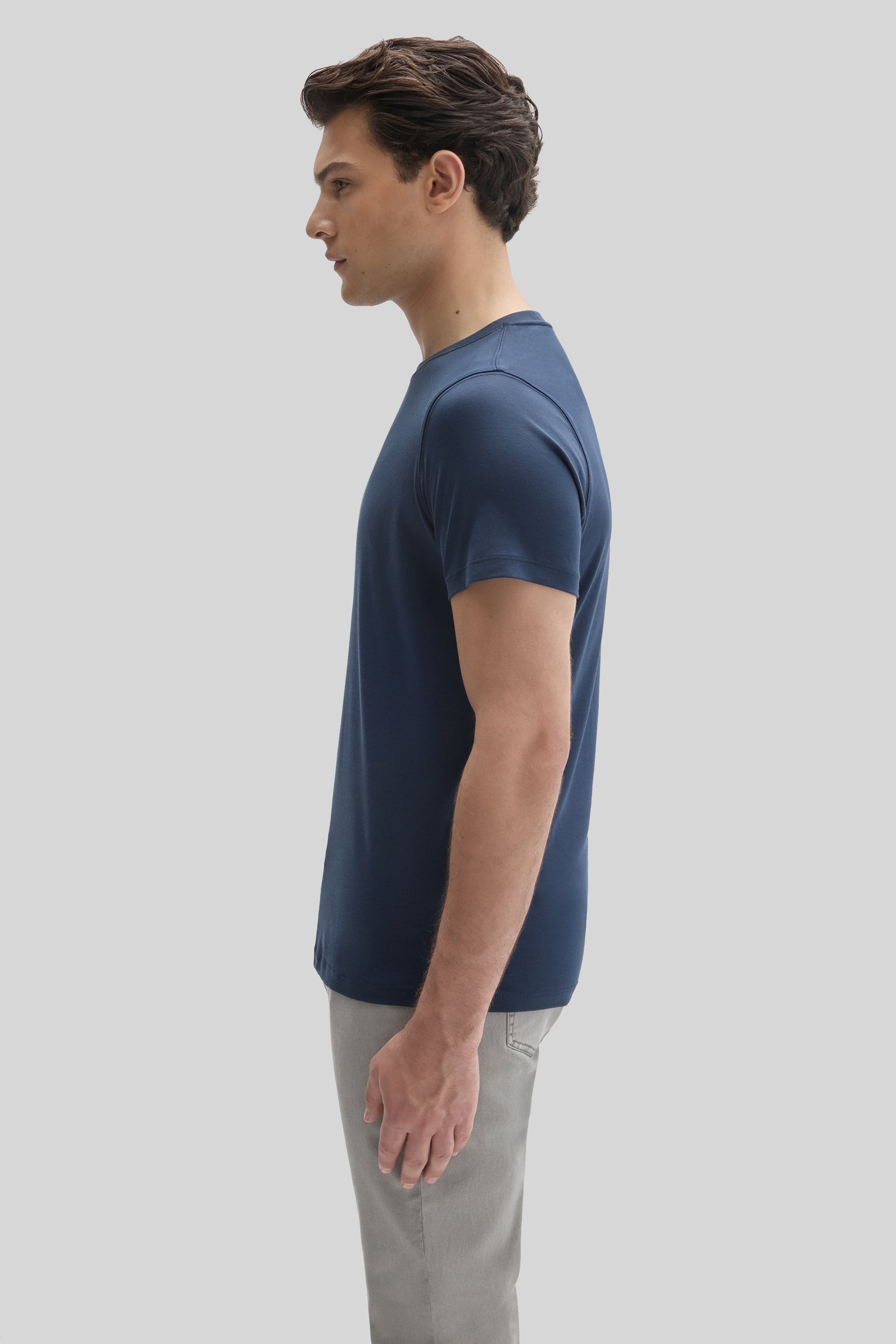 Man wearing navy blue short-sleeve t-shirt with gray pants, shown in profile view.