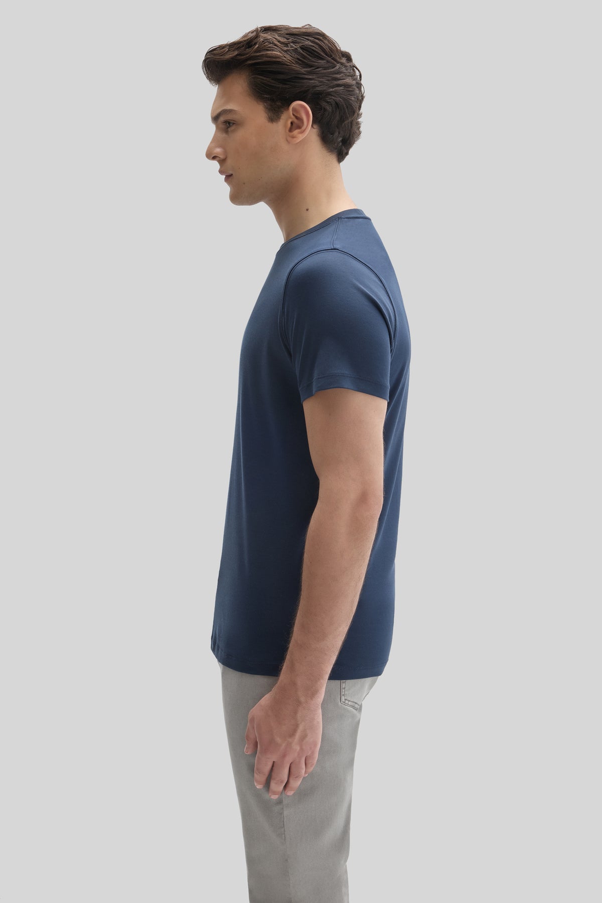 Man wearing navy blue short-sleeve t-shirt with gray pants, shown in profile view.