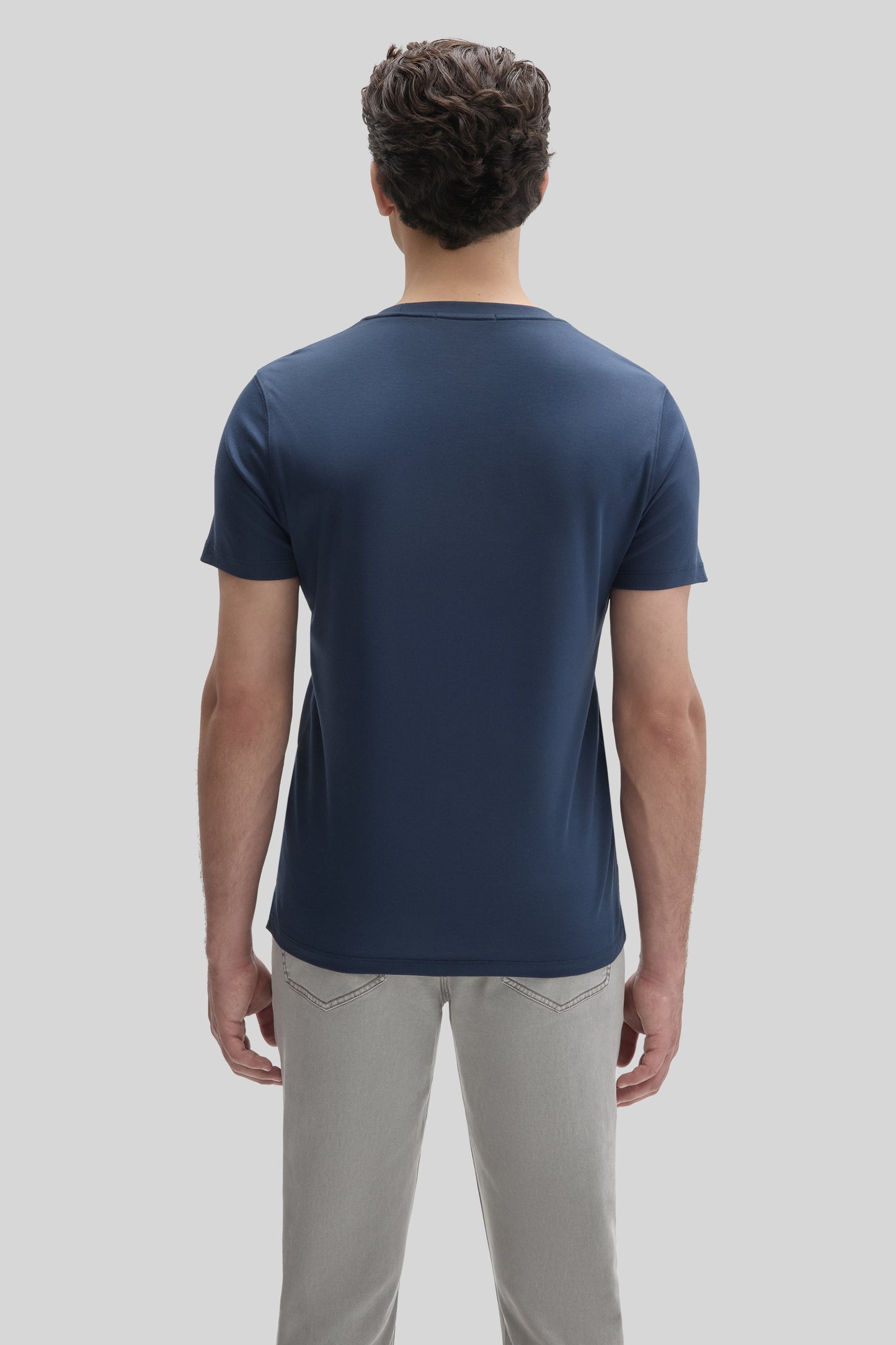 Man wearing a navy blue short-sleeve t-shirt with light gray pants, shown from behind.