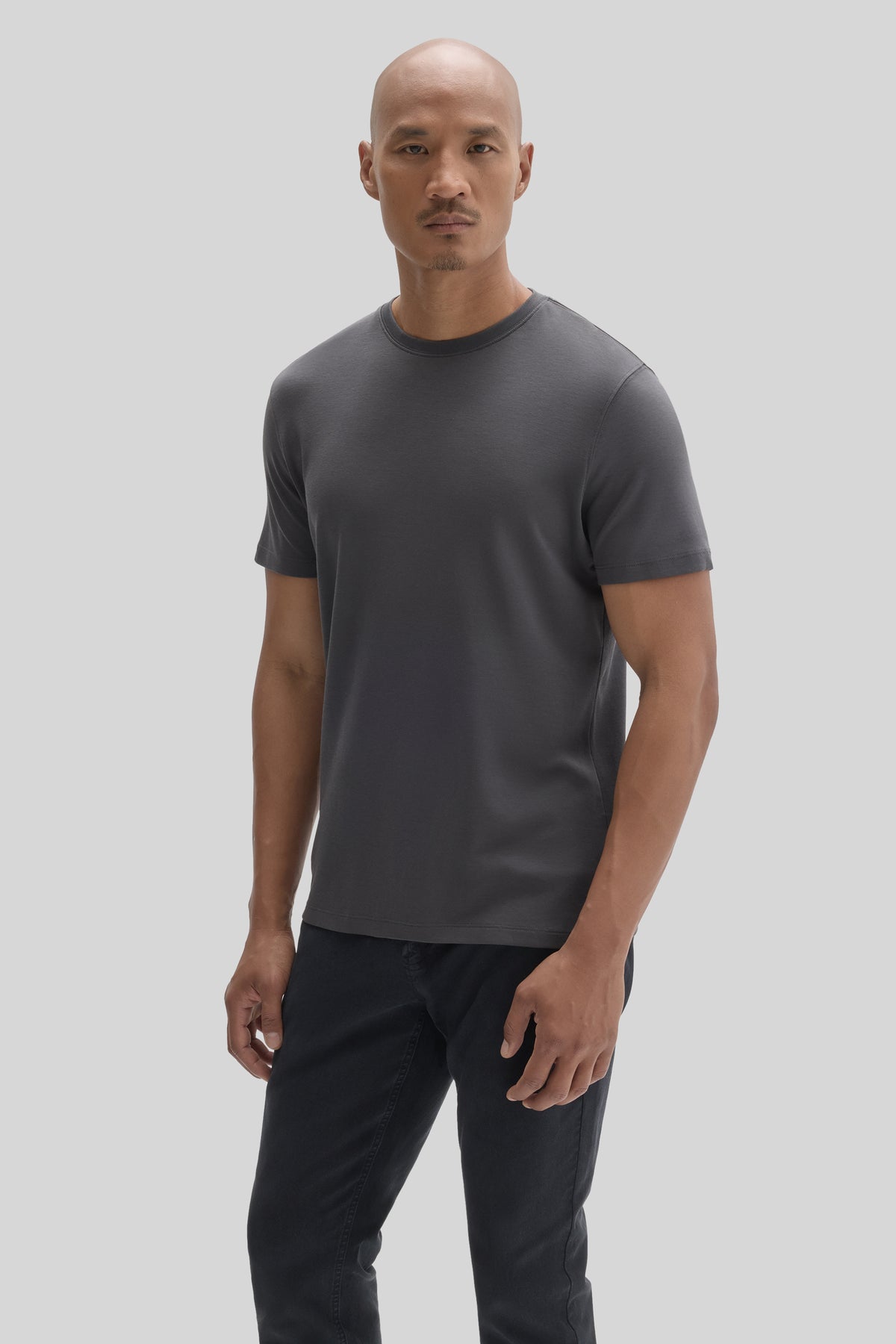 Man wearing a dark gray short-sleeve crew neck t-shirt with black pants.