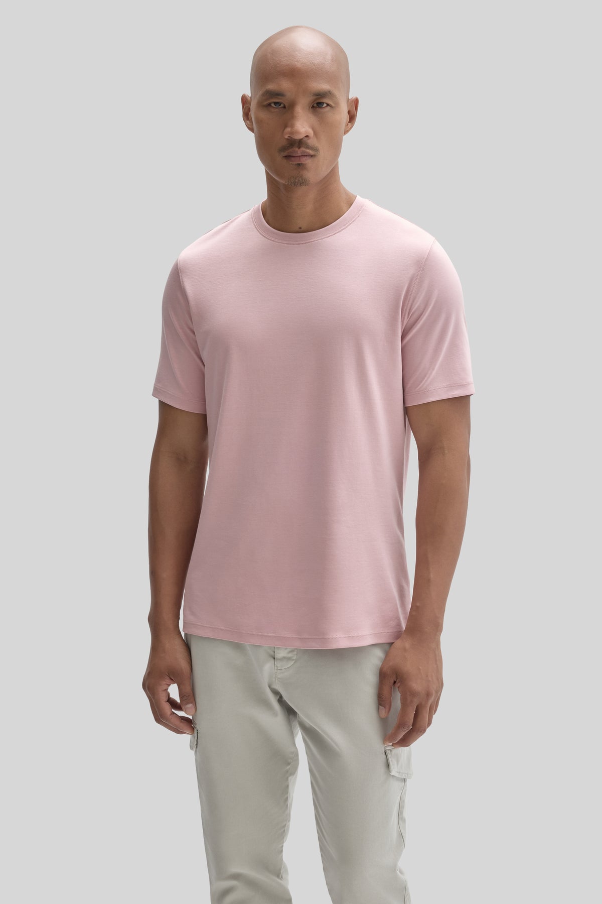 Man wearing light pink short-sleeve crew neck t-shirt with cream cargo pants.