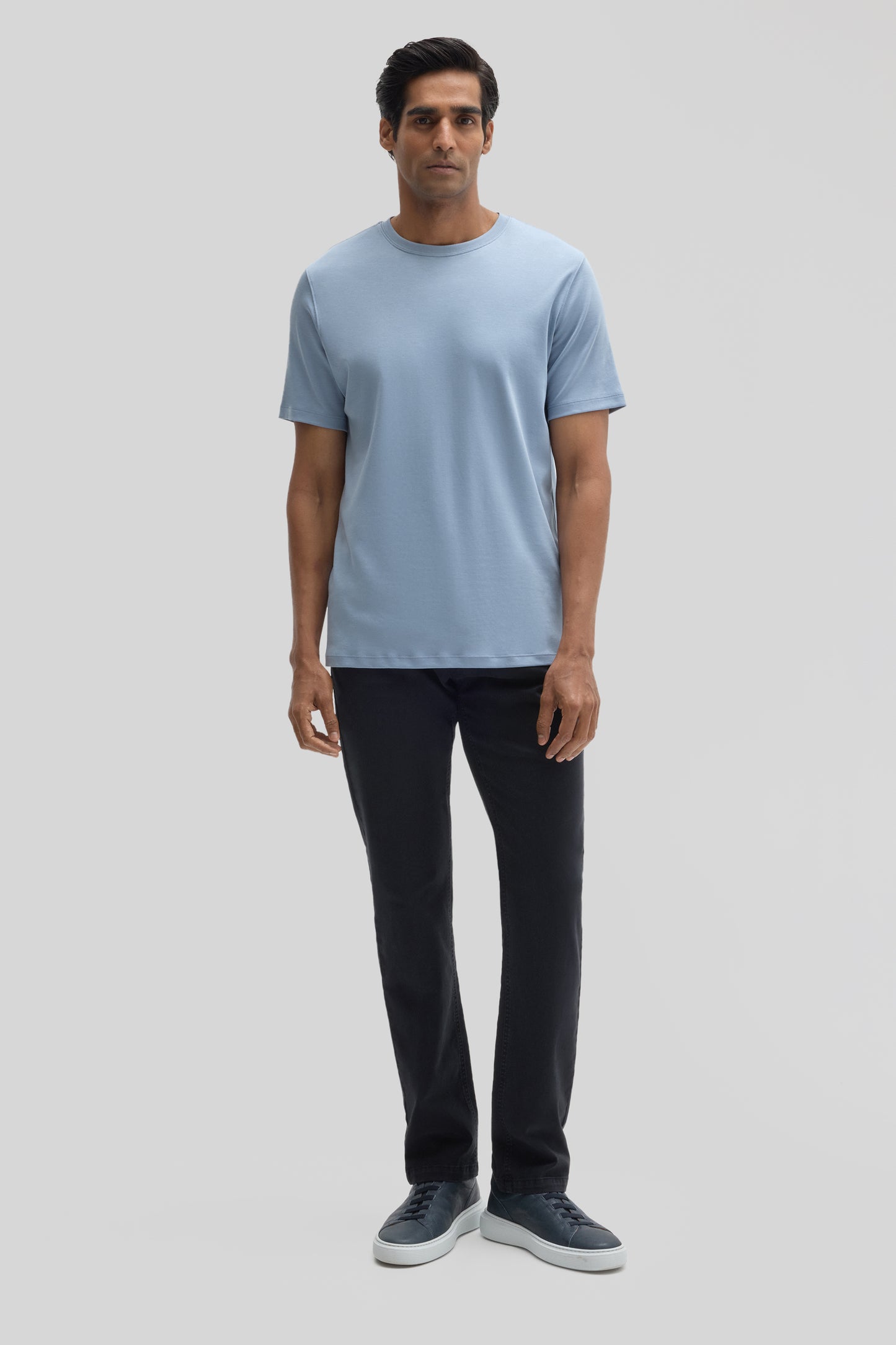 Man wearing light blue crew-neck t-shirt with short sleeves and black pants.