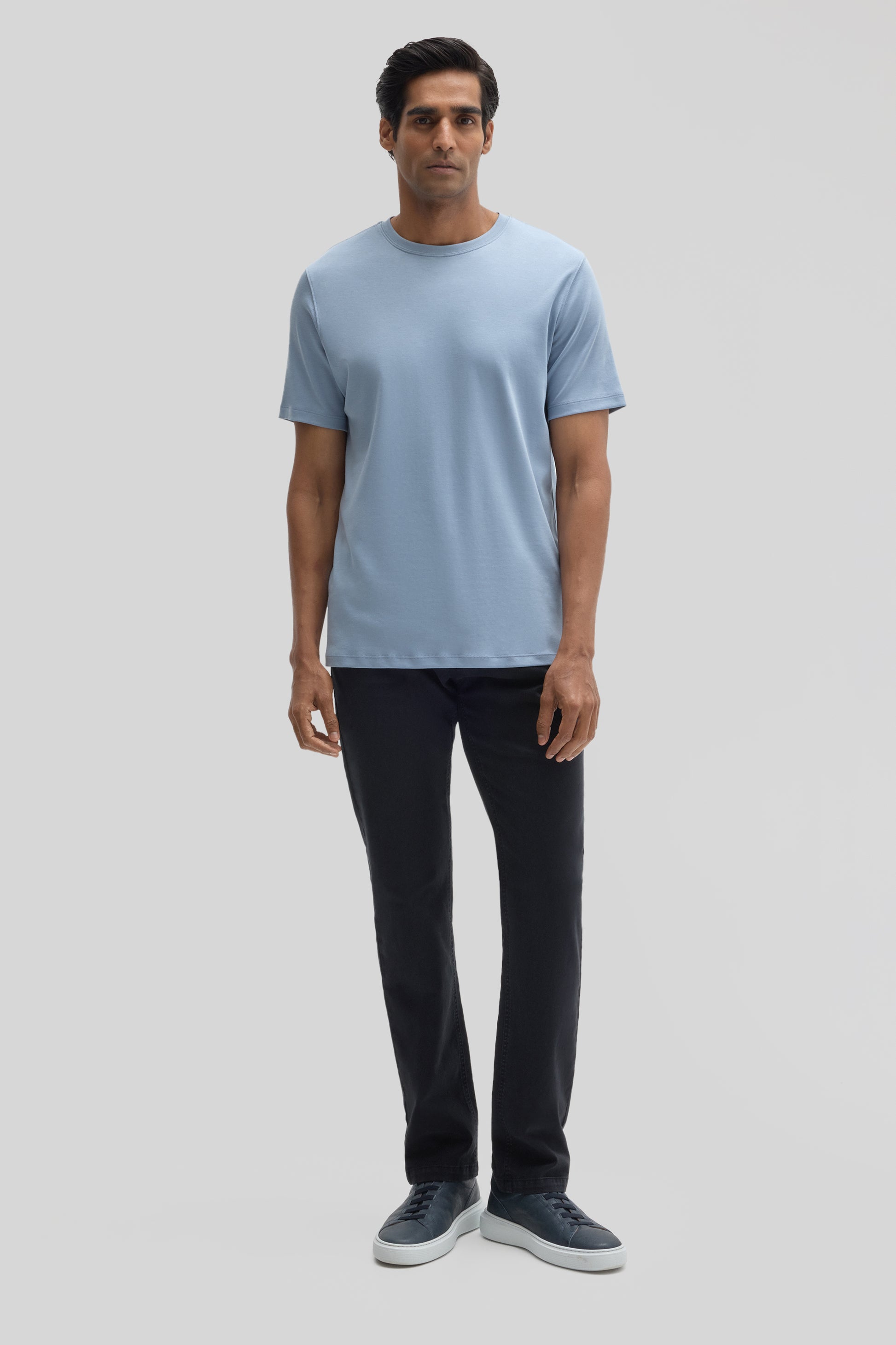 Man wearing light blue crew-neck t-shirt with short sleeves and black pants.