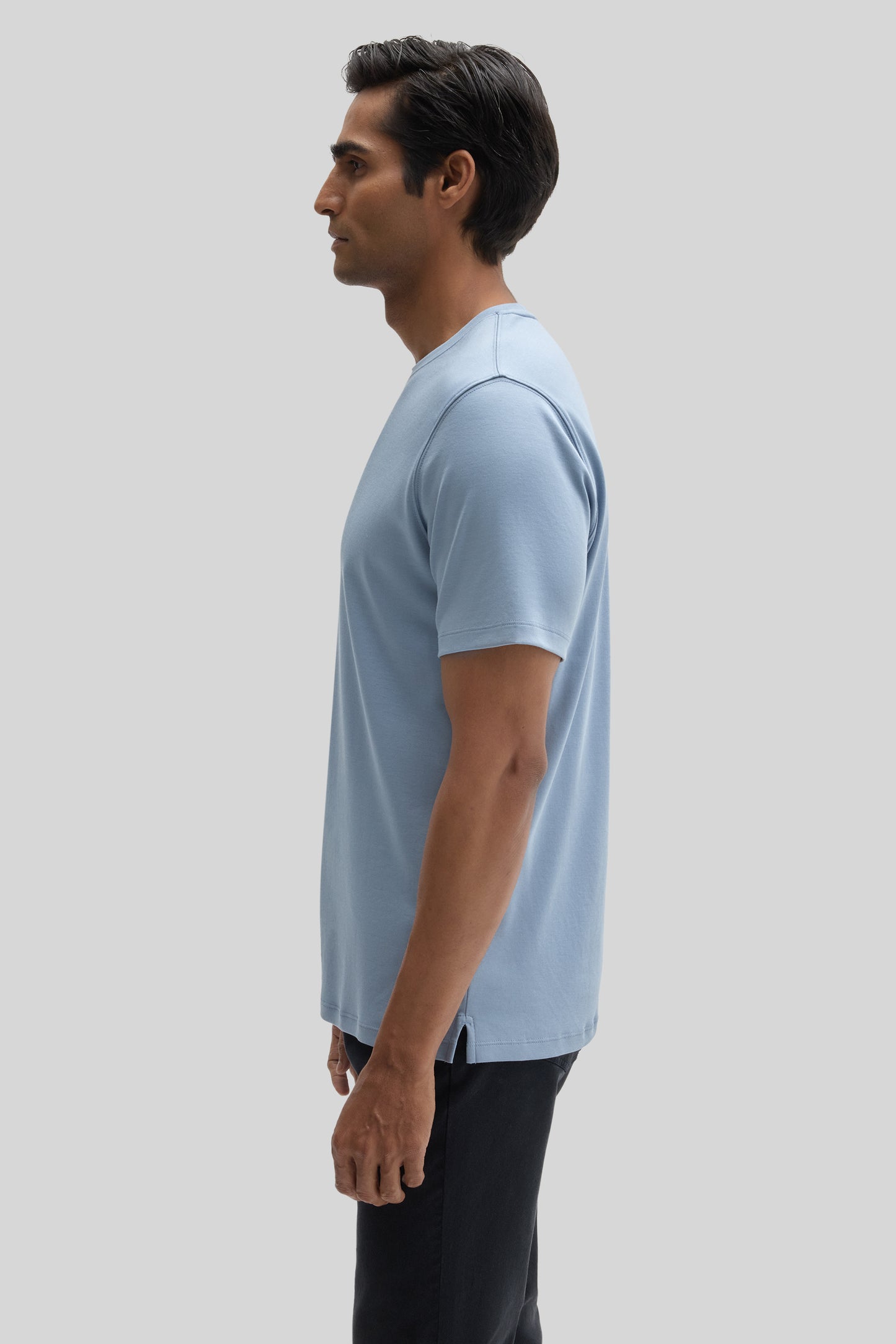 Man wearing light blue short-sleeve t-shirt with black pants, shown in side profile.
