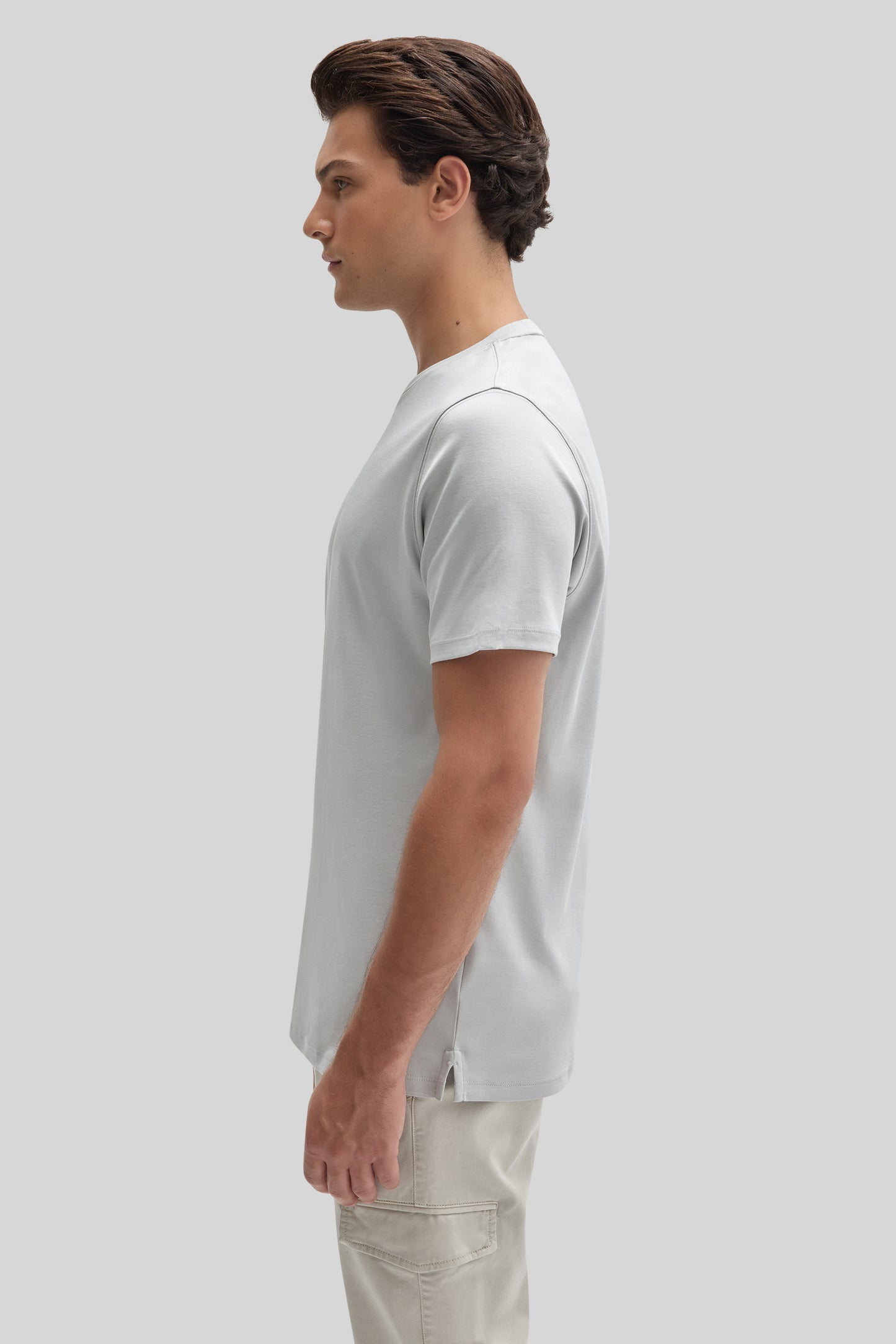 Man wearing white short-sleeve t-shirt with cream-colored pants, shown in side profile.