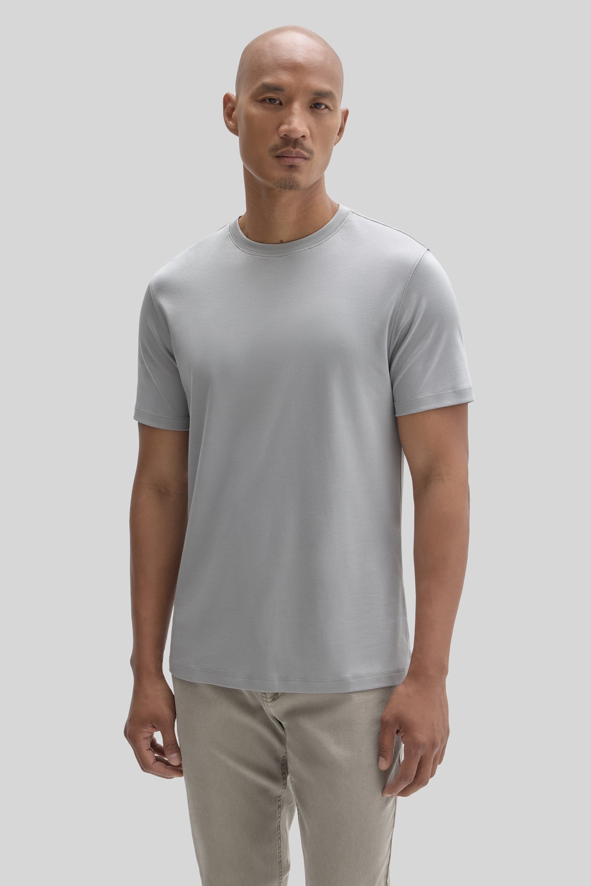 Man wearing a light gray short-sleeve crew neck t-shirt with beige pants.