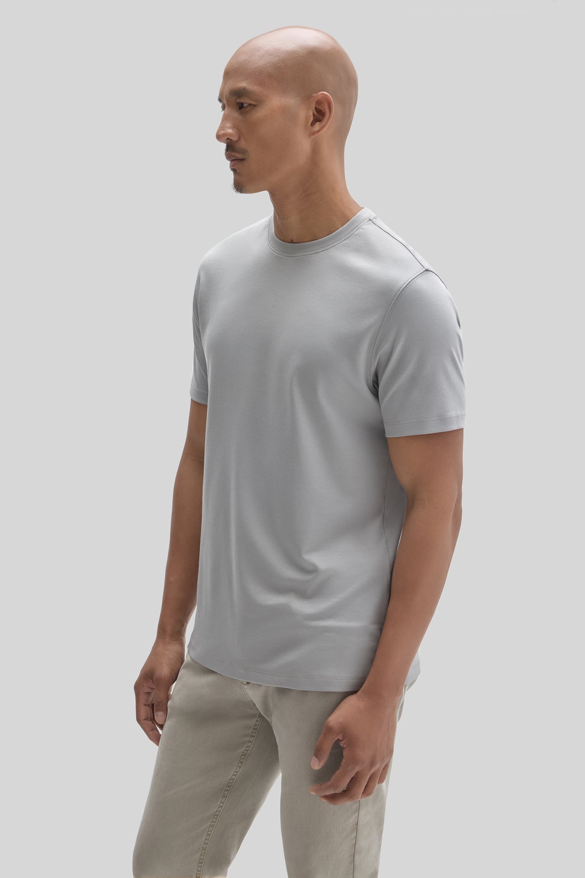 Man wearing light gray crew-neck t-shirt with short sleeves, paired with beige pants.