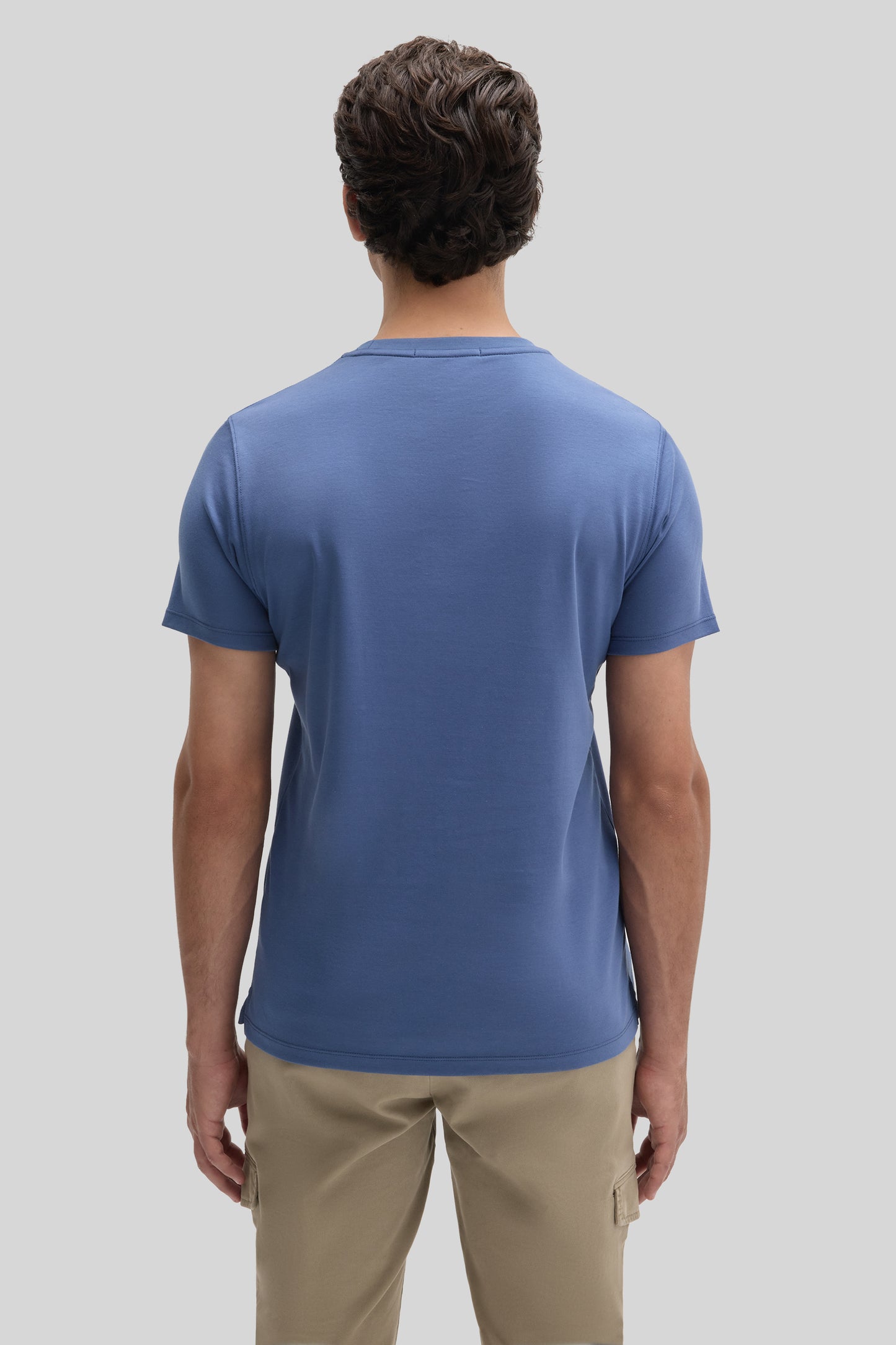 Man wearing blue short-sleeve t-shirt and beige cargo pants, shown from back view.