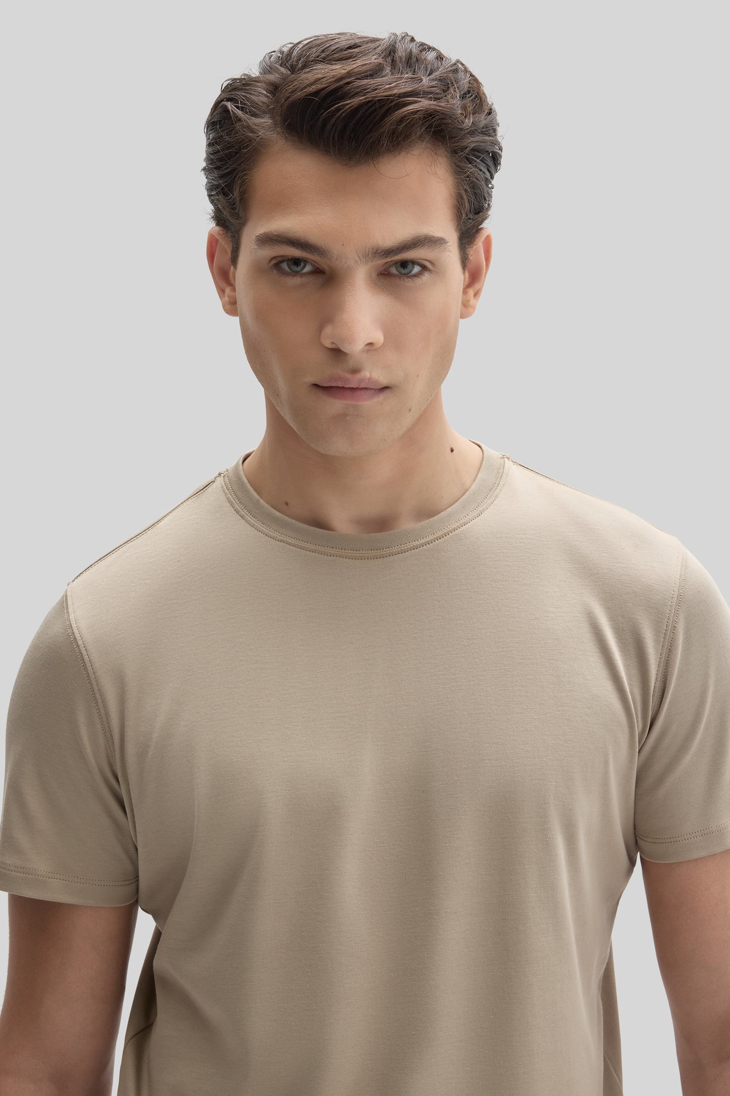 Man wearing a beige crew-neck short-sleeve t-shirt against a neutral background.