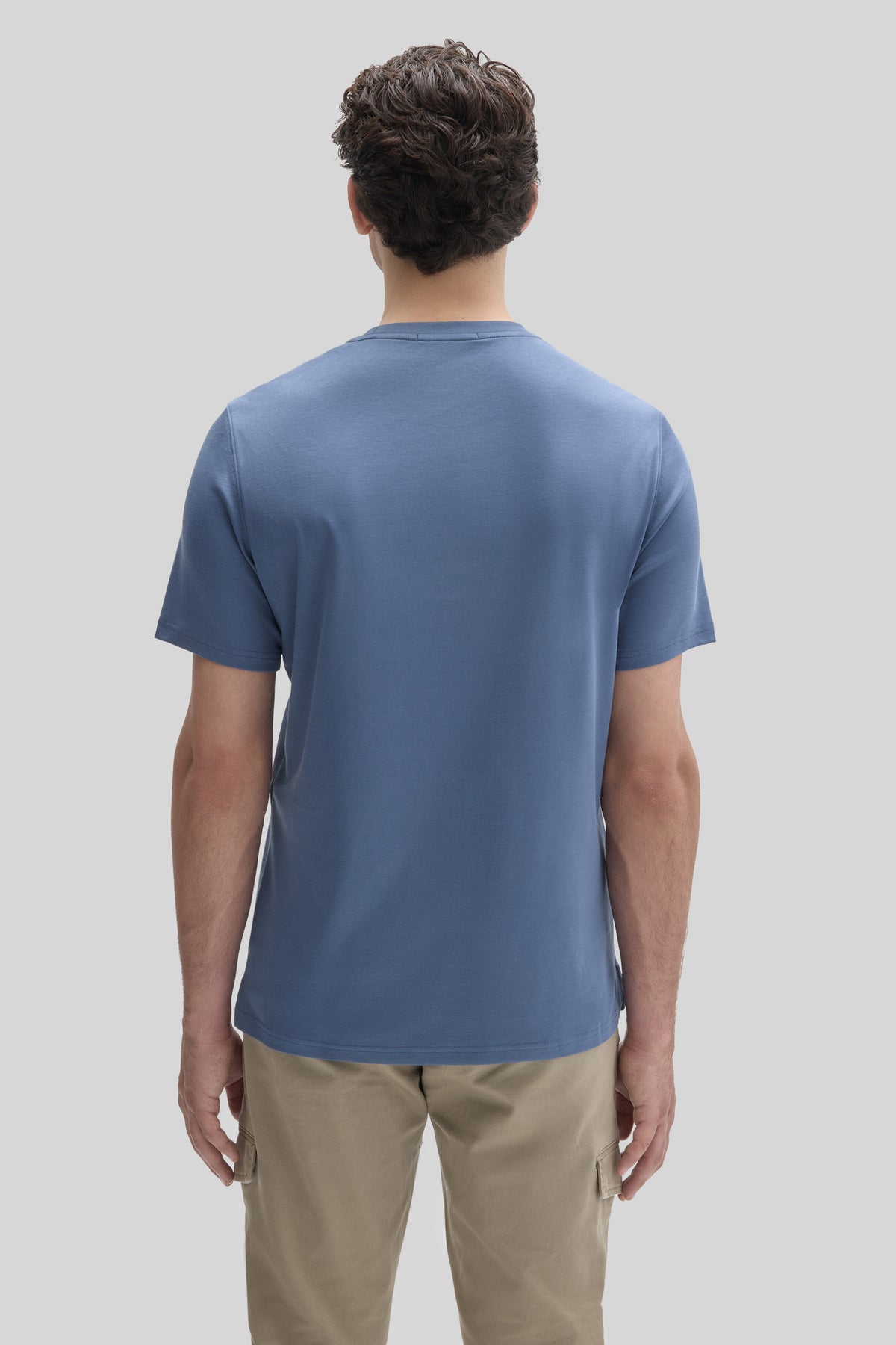Man wearing blue short-sleeve t-shirt and beige cargo pants, shown from back view.
