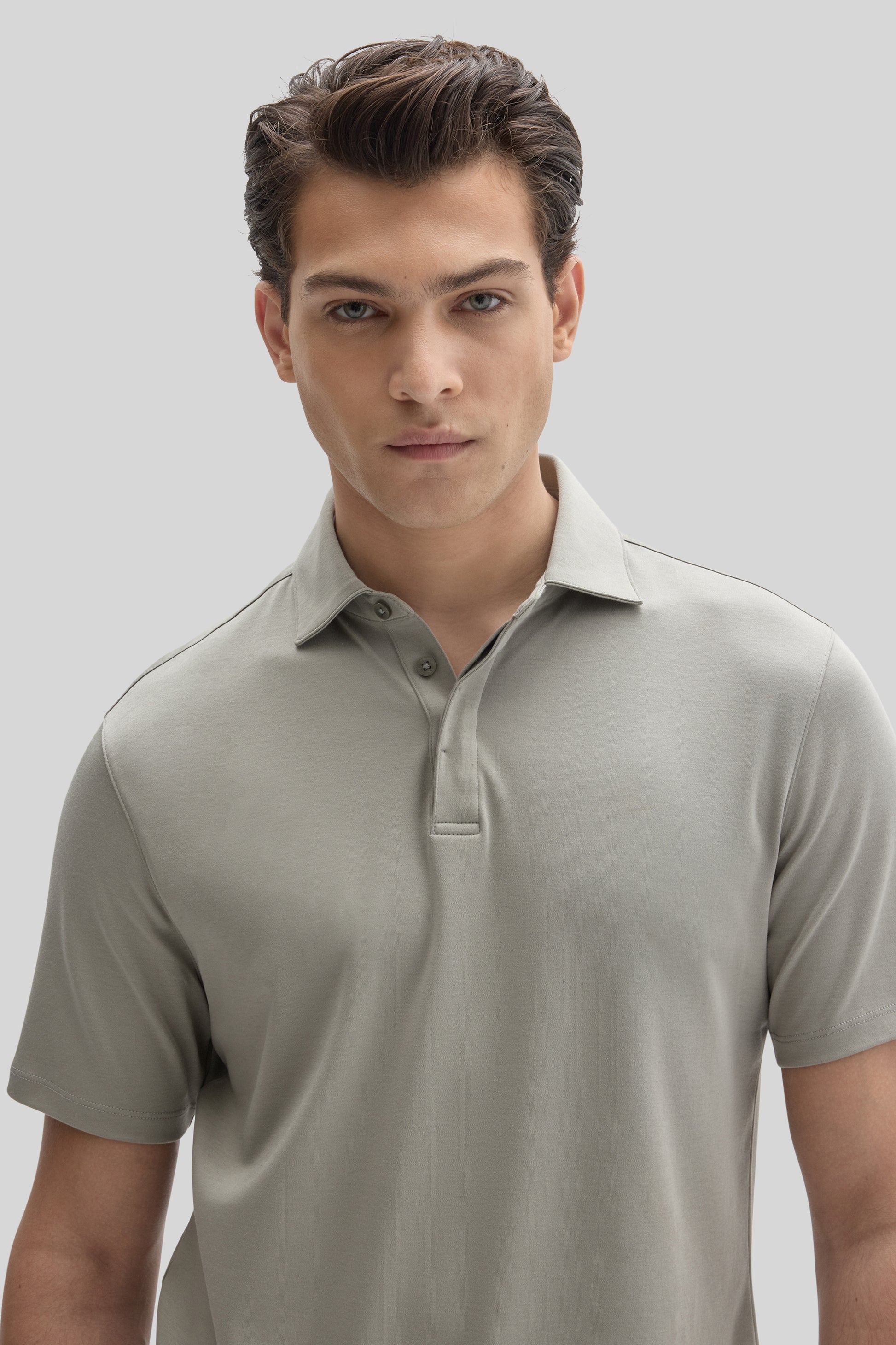 Man wearing light gray short-sleeve polo shirt with covered placket and collar detail.