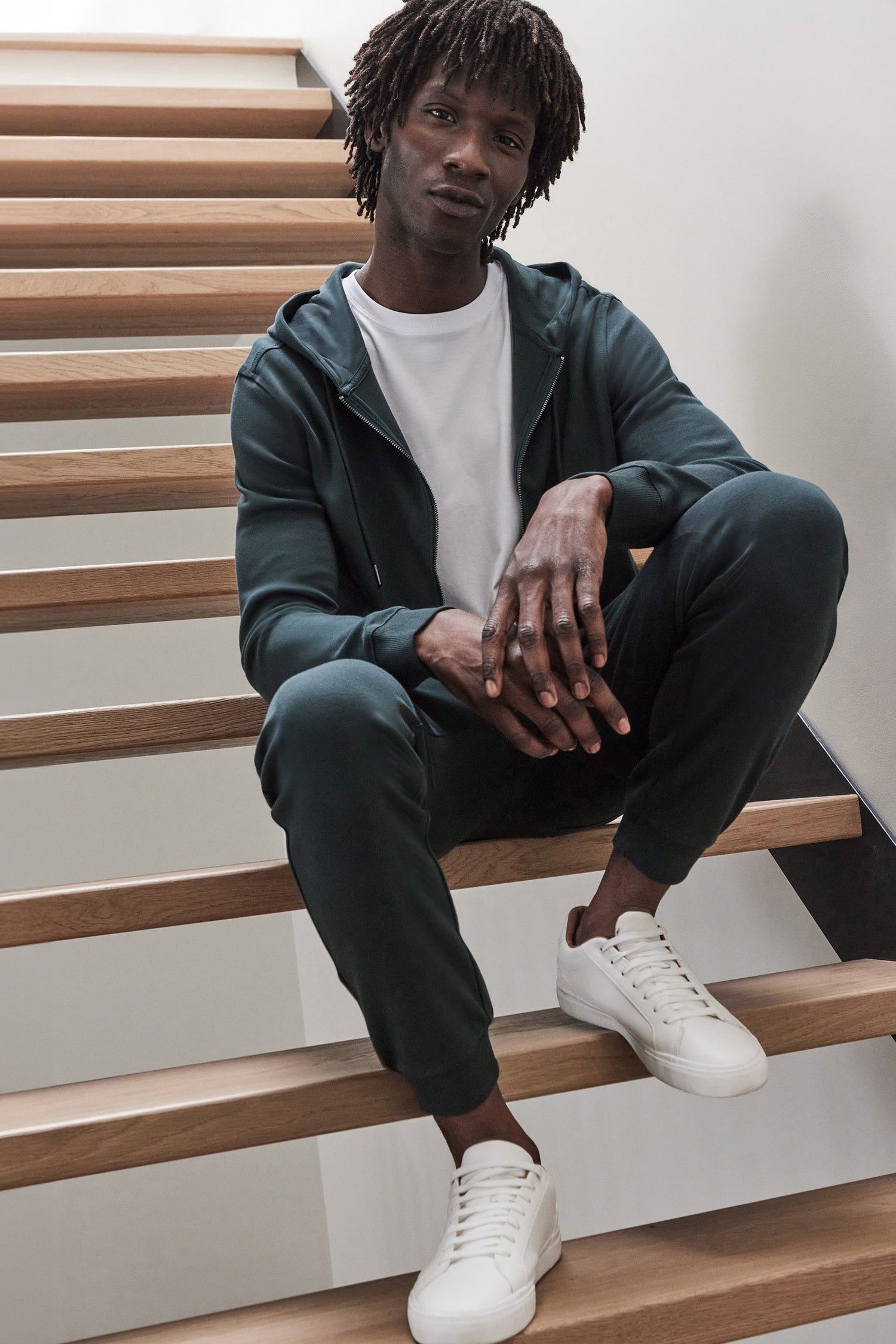 Man sitting on stairs wearing the Cortina hoodie and joggers