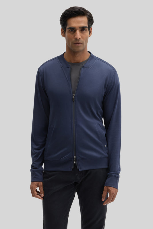 Man wearing navy blue baseball jacket with full-length zip and ribbed cuffs over black pants.
