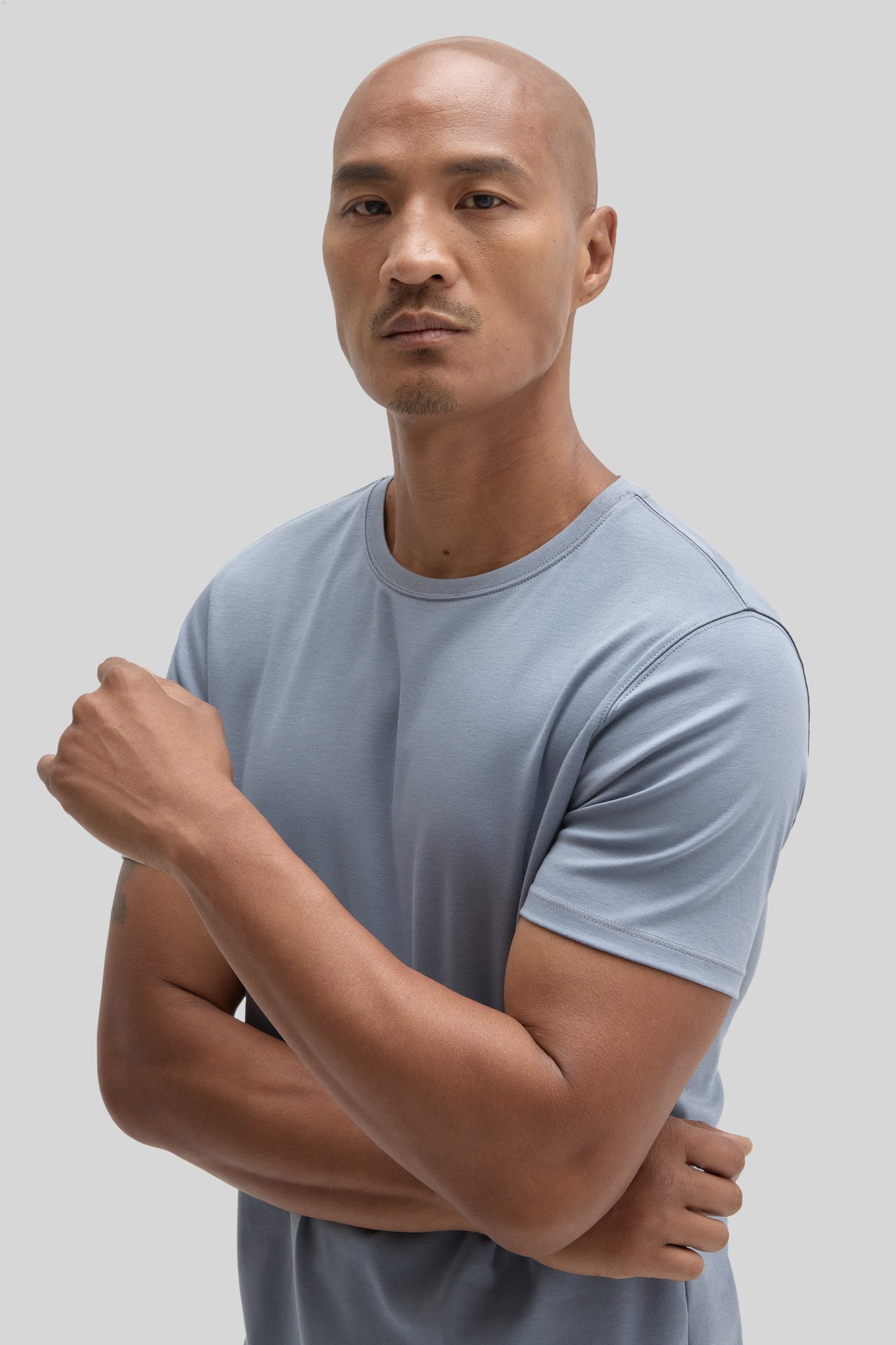 Man wearing light blue crew neck short-sleeve t-shirt with arms crossed.