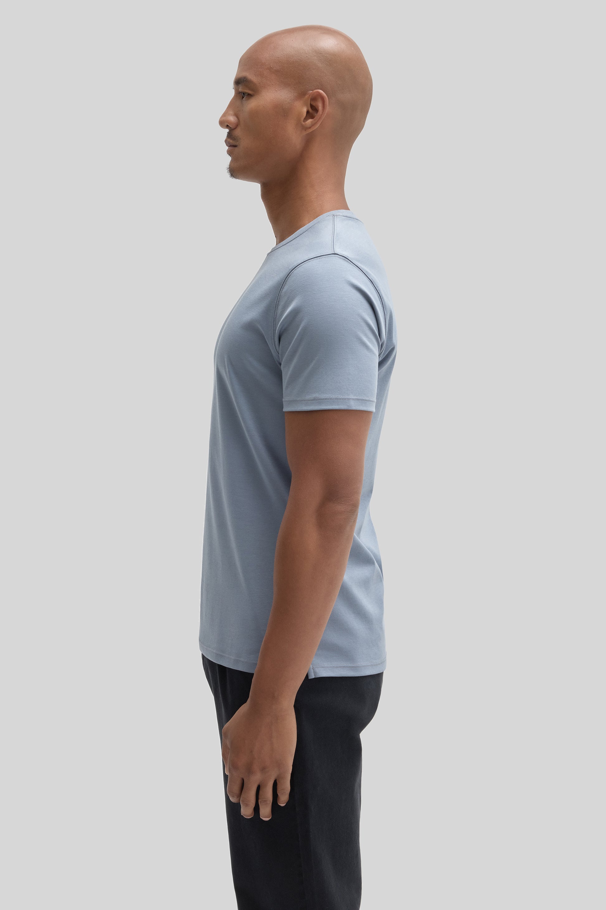 Man wearing light blue short-sleeve t-shirt with black pants, shown in side profile.