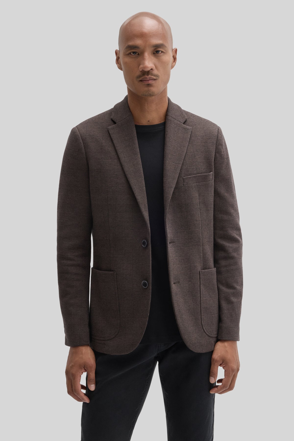 Brown plaid sport coat with notch lapels and two-button closure worn over black shirt.