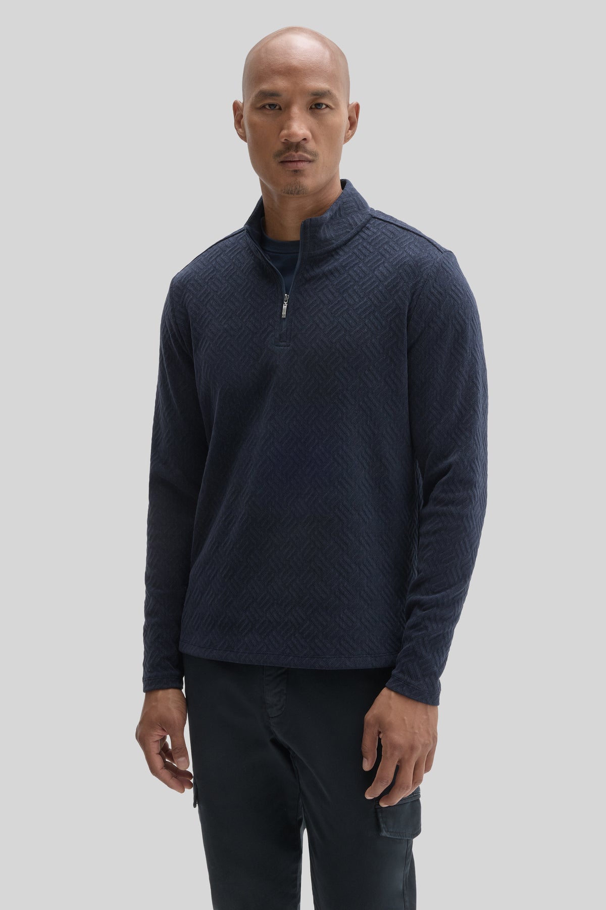 Navy quarter-zip pullover with textured weave pattern and stand collar worn with black pants.