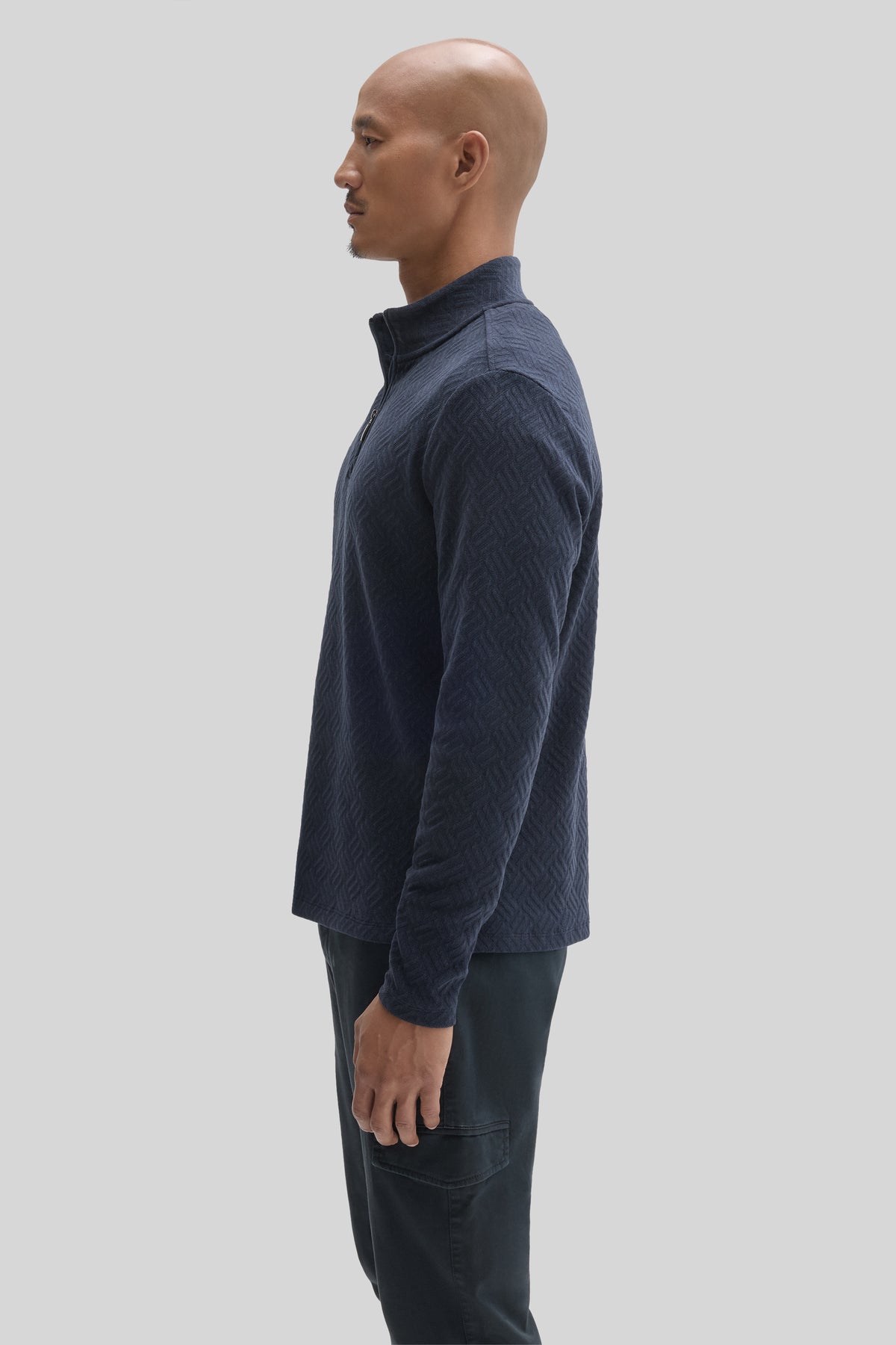 Navy blue textured quarter-zip pullover with long sleeves and stand collar, worn with dark pants.