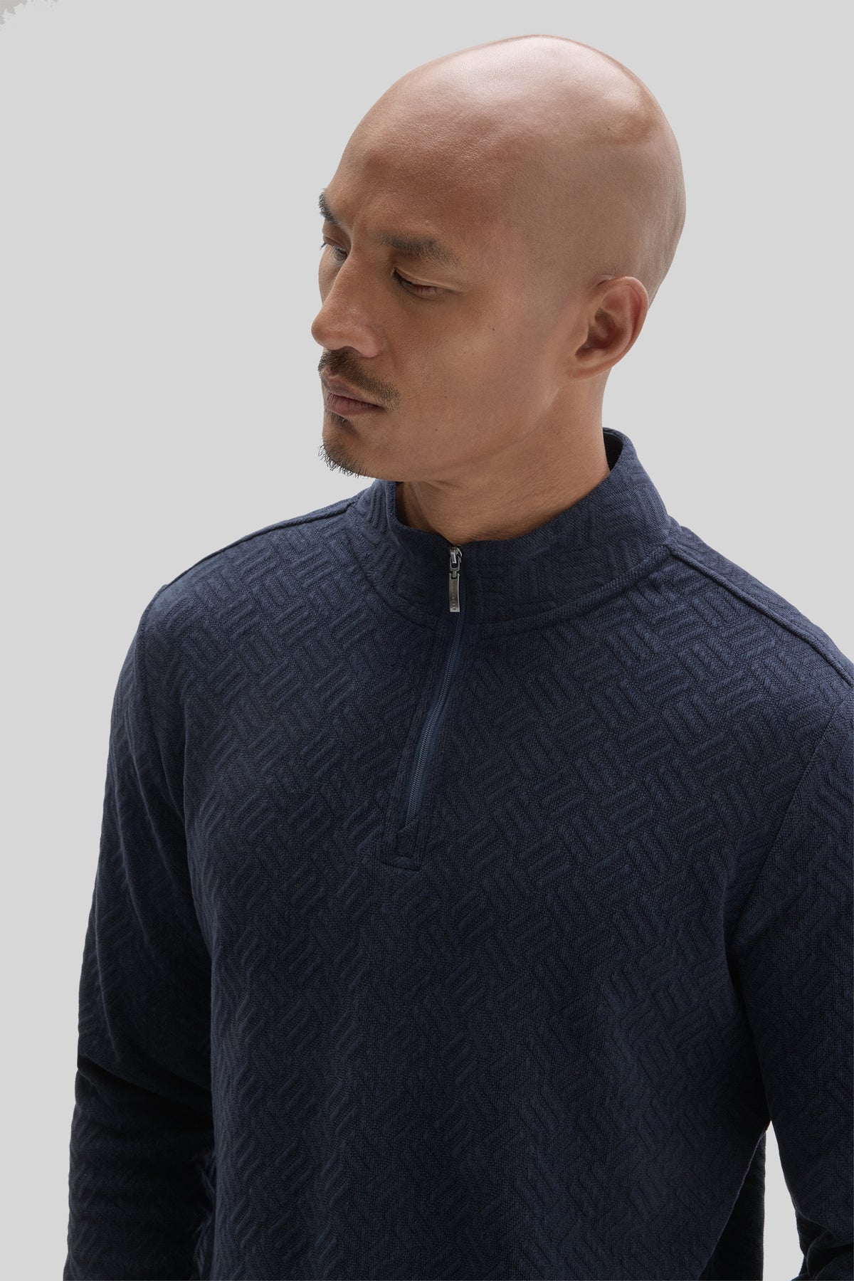 Navy long-sleeve quarter zip pullover with textured geometric pattern worn by model in profile view.