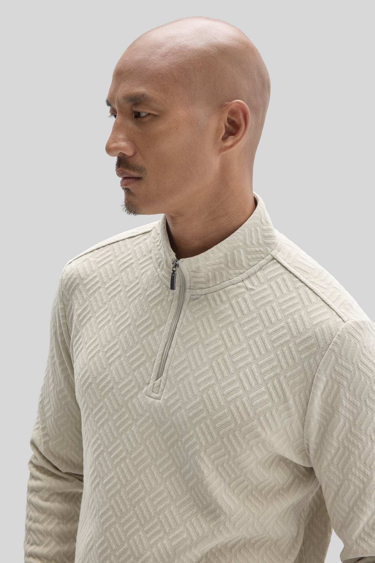 Cream-colored long sleeve pullover with quarter zip and geometric quilted pattern on front and sleeves.