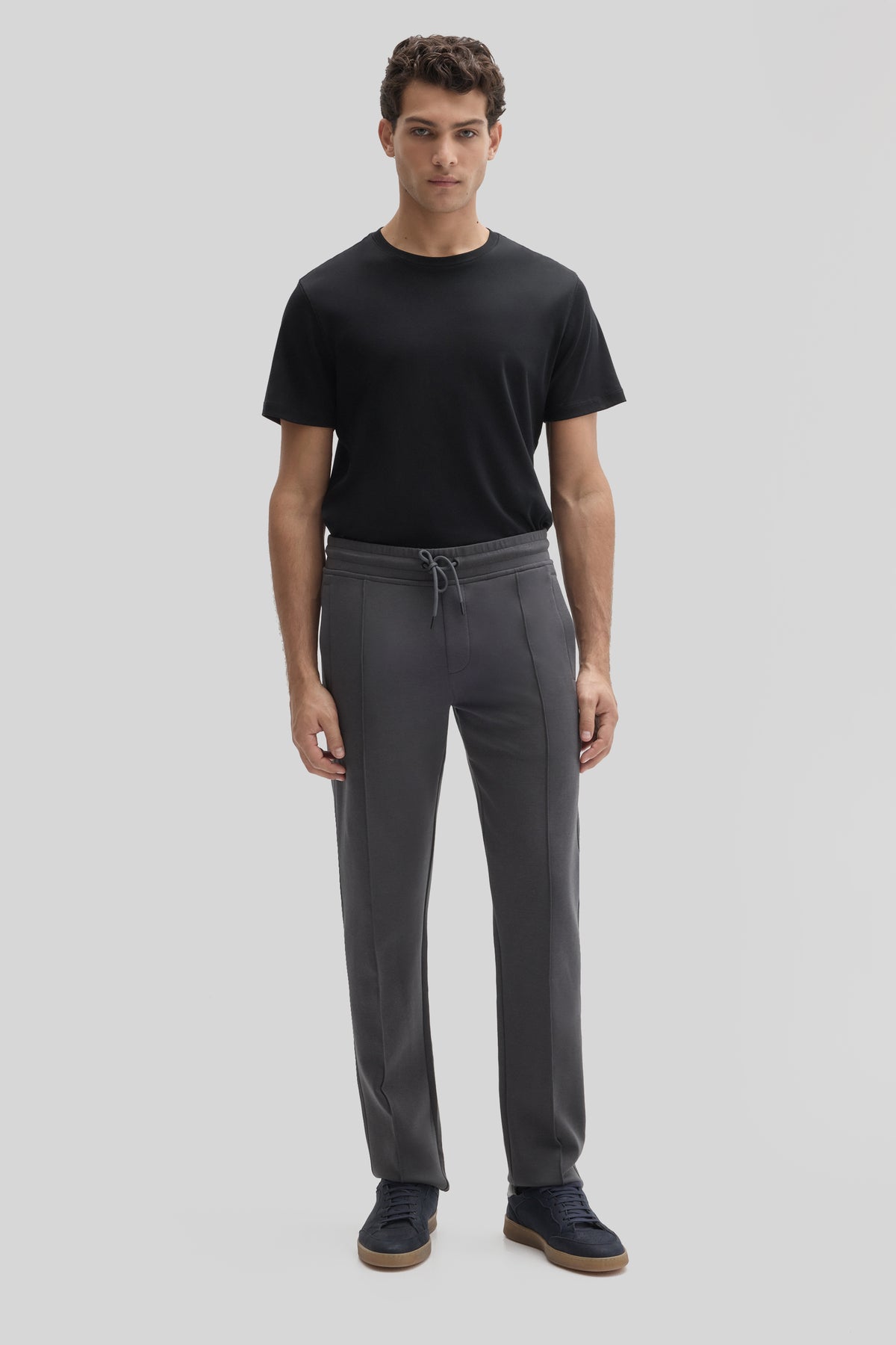 Men's charcoal gray jogging pants with drawstring waist and vertical seam details, worn with black t-shirt.
