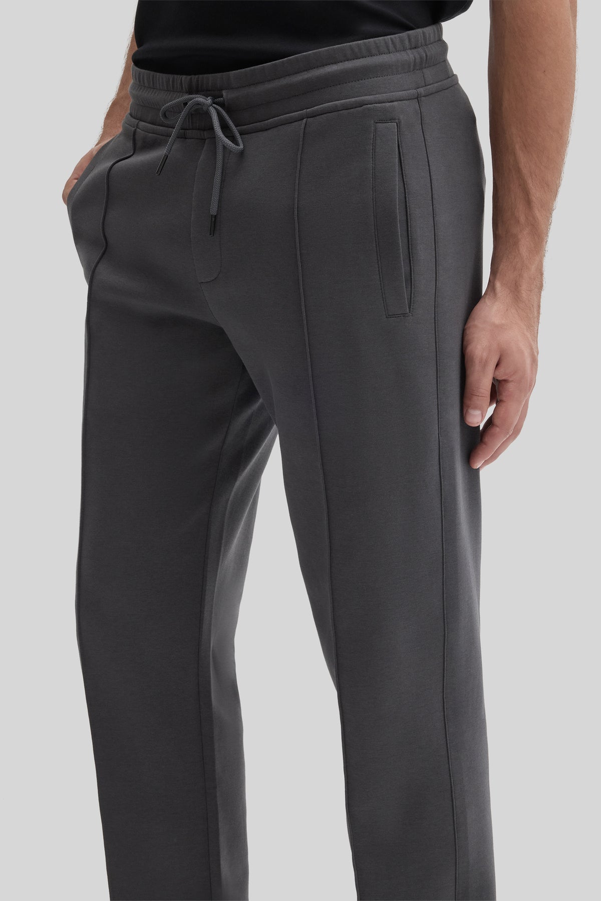 Charcoal gray jogging pants with drawstring waist, side pockets, and vertical seam details on legs.