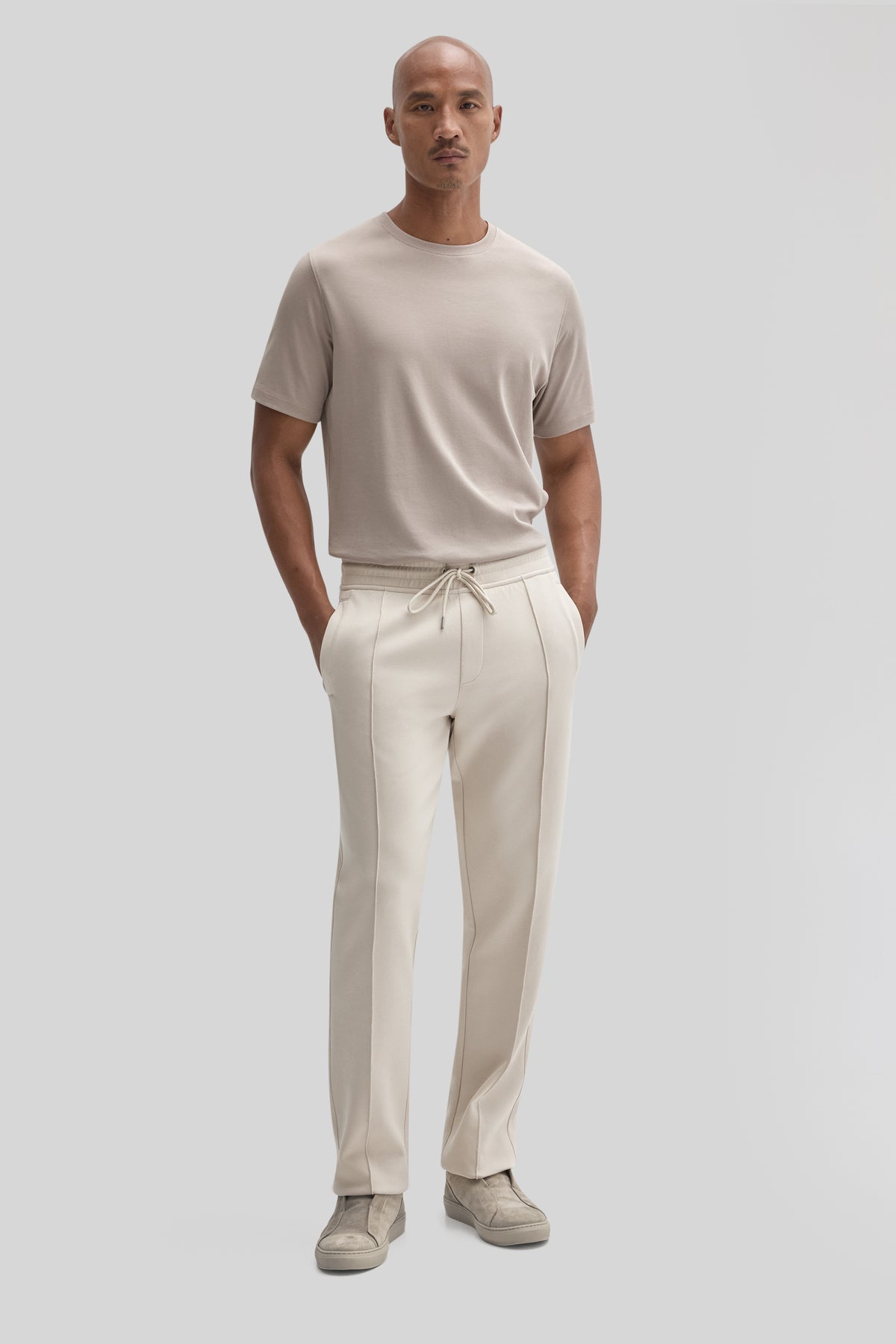 Man wearing beige jogging pants with drawstring waist and side pockets, paired with a tan t-shirt.