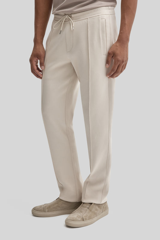 Cream-colored jogging pants with drawstring waist, side pockets, and contrast stitching on legs.