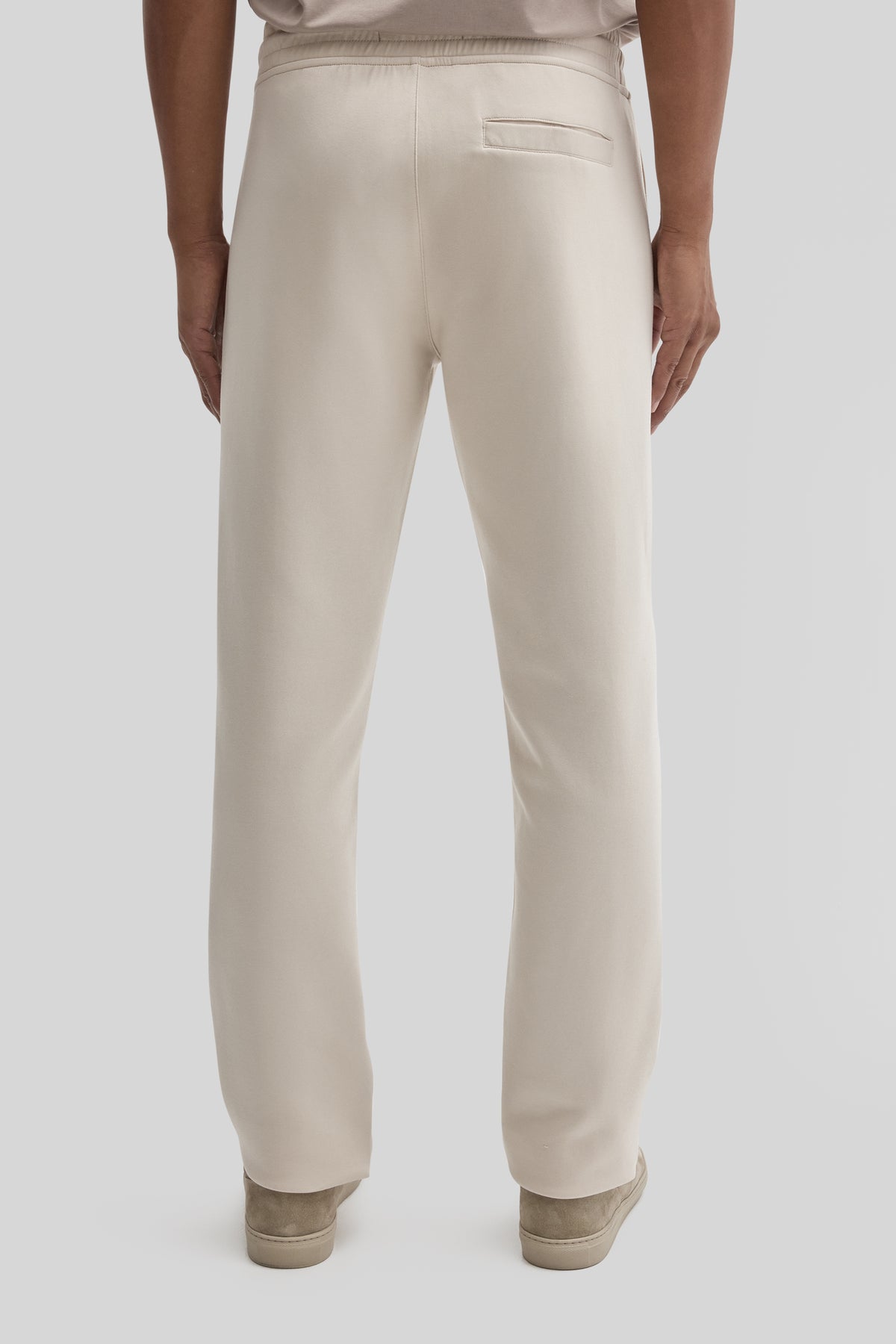 Cream jogging pants with back pocket and ribbed cuffs, shown from behind.