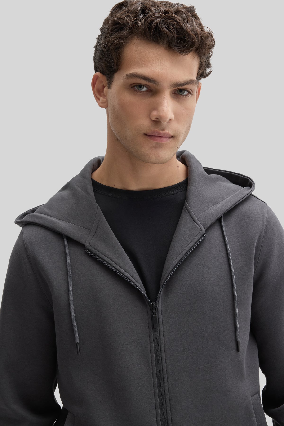 Man wearing charcoal gray full-zip hoodie with black undershirt and drawstring hood.